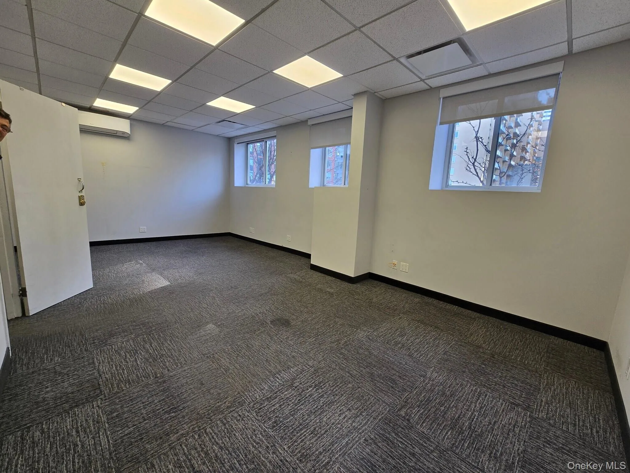Carpeted spare room with a drop ceiling and a wall mounted air conditioner Carpeted spare room with a drop ceiling and a wall mounted air conditioner