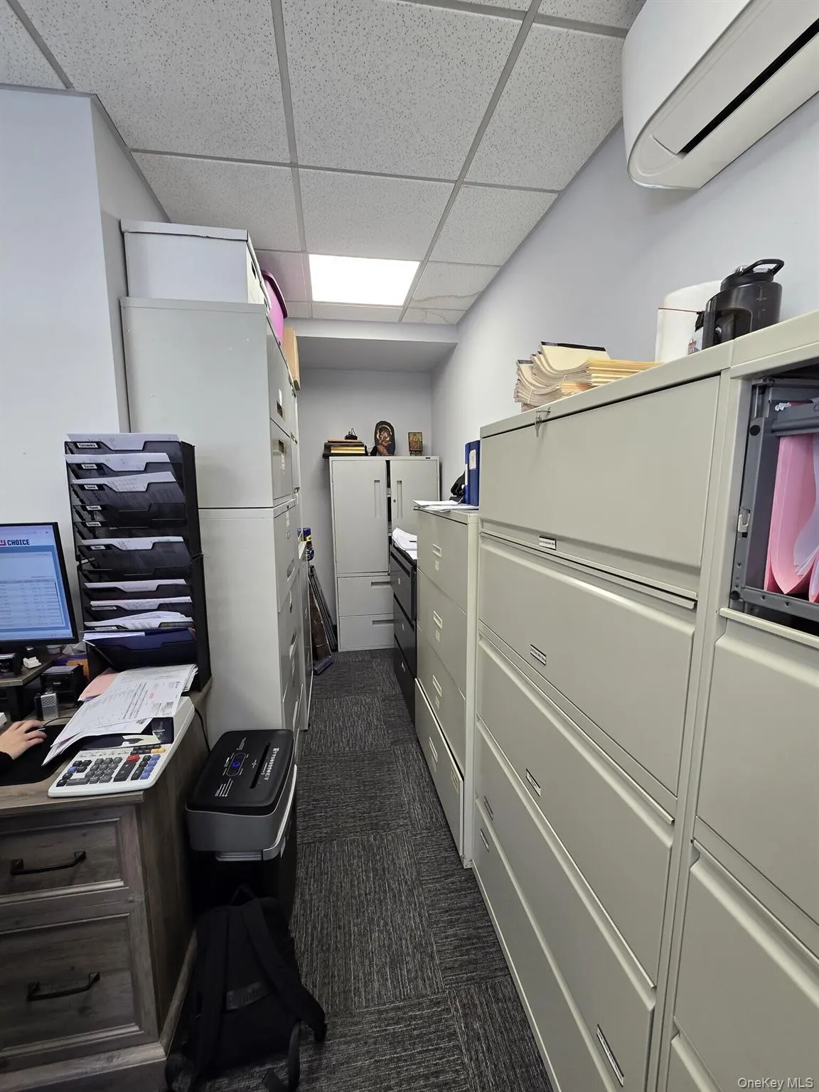 Home office featuring a drop ceiling, a wall mounted AC, and dark carpet Home office featuring a drop ceiling, a wall mounted AC, and dark carpet
