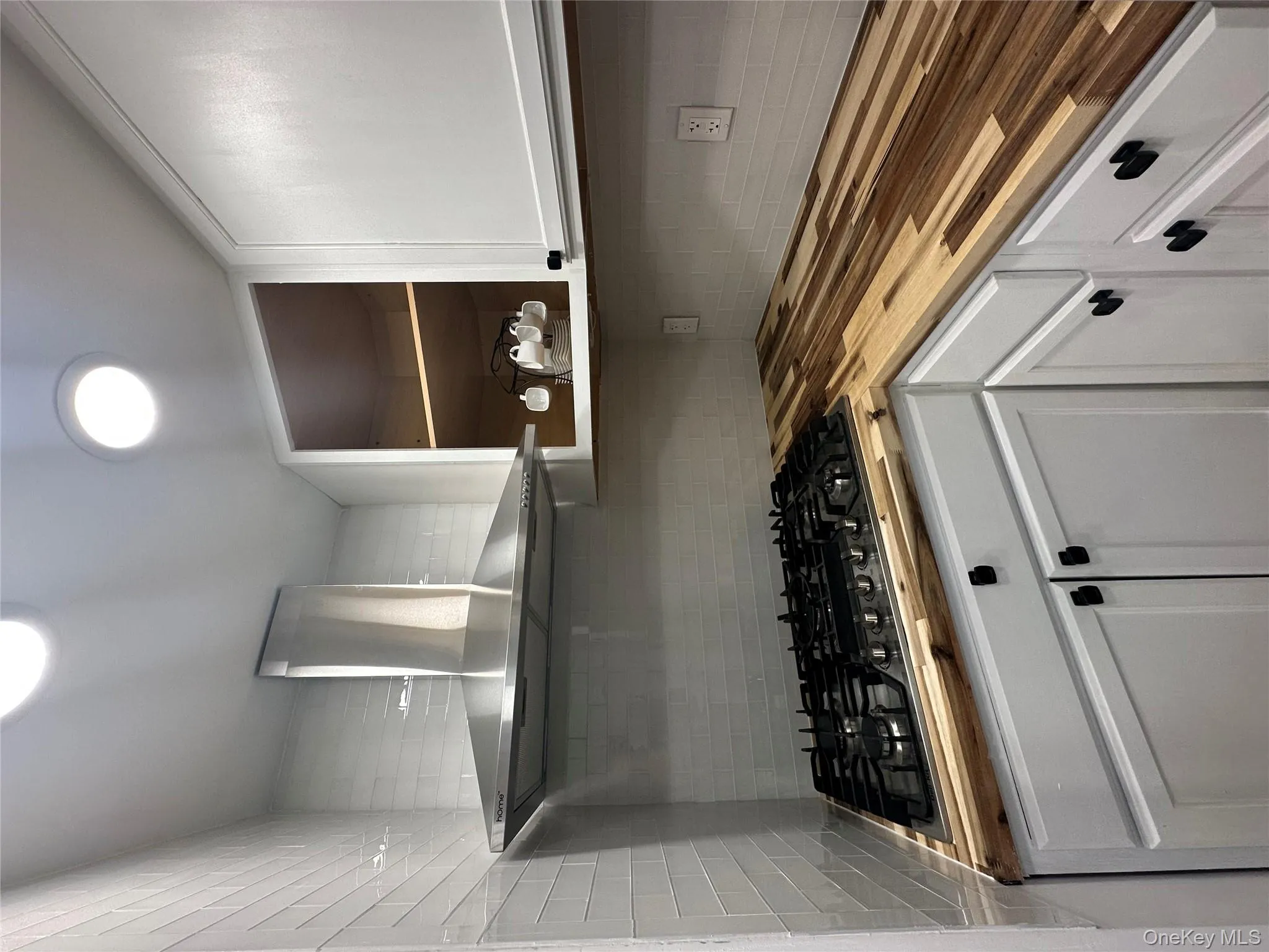 Kitchen with cooktop, butcher block counters, backsplash, and ventilation hood Kitchen with cooktop, butcher block counters, backsplash, and ventilation hood