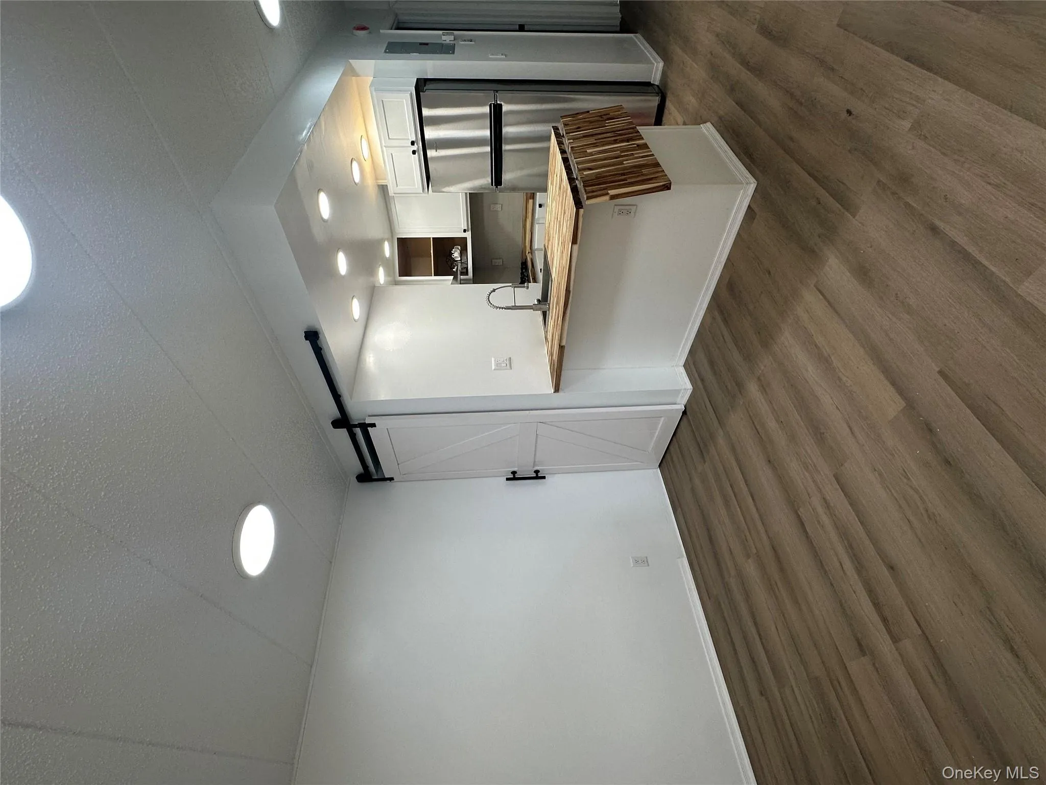 Kitchen with refrigerator, a barn door, butcher block countertops, a peninsula, and dark wood-style floors Kitchen with refrigerator, a barn door, butcher block countertops, a peninsula, and dark wood-style floors