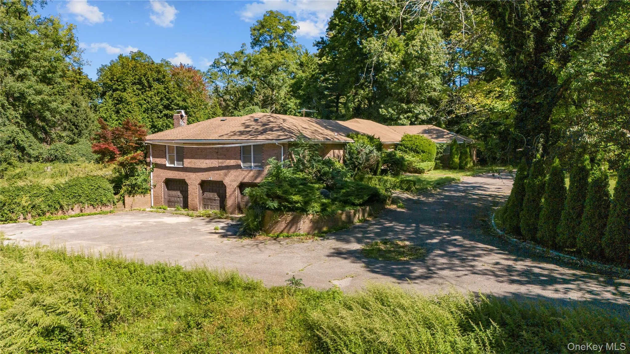 View of front of home featuring driveway, brick siding, a chimney, and view of side driveway View of front of home featuring driveway, brick siding, a chimney, and view of side driveway