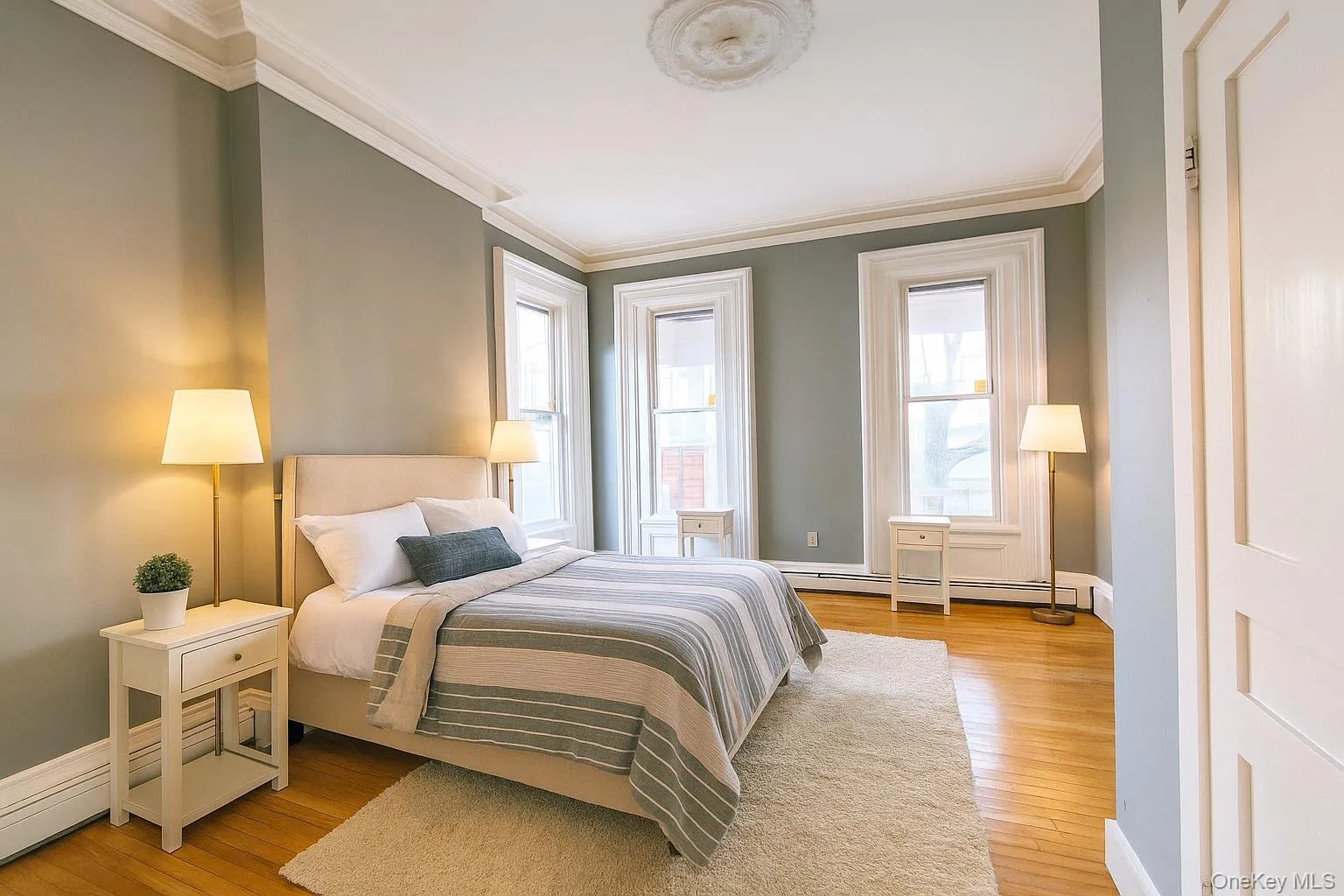 Bedroom with ornamental molding, light wood-type flooring, and a baseboard radiator Bedroom with ornamental molding, light wood-type flooring, and a baseboard radiator