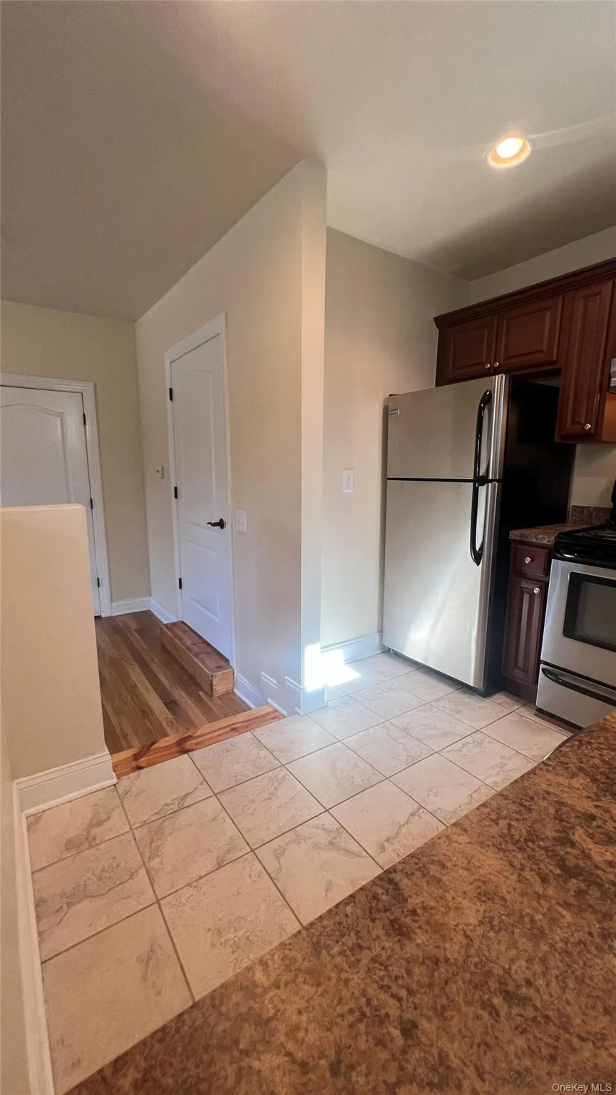 Kitchen with stainless steel range with electric cooktop, light tile patterned floors, dark brown cabinetry, and recessed lighting Kitchen with stainless steel range with electric cooktop, light tile patterned floors, dark brown cabinetry, and recessed lighting