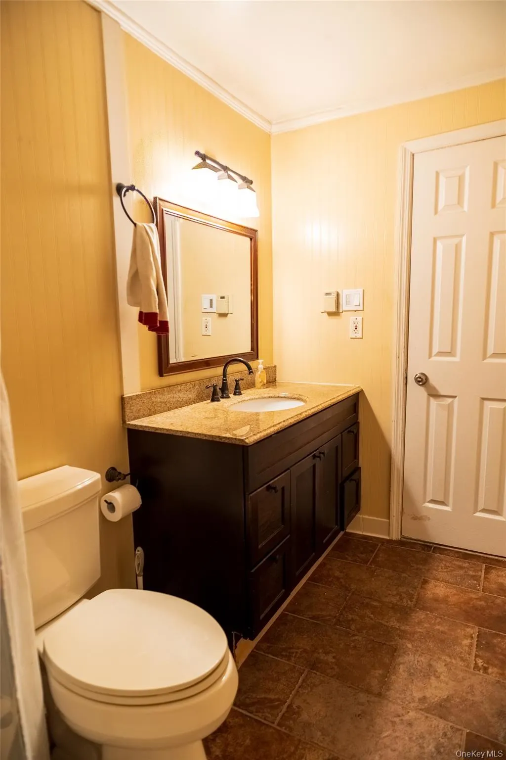 Bathroom with vanity, crown molding, wooden walls, and dark stone finish floors Bathroom with vanity, crown molding, wooden walls, and dark stone finish floors