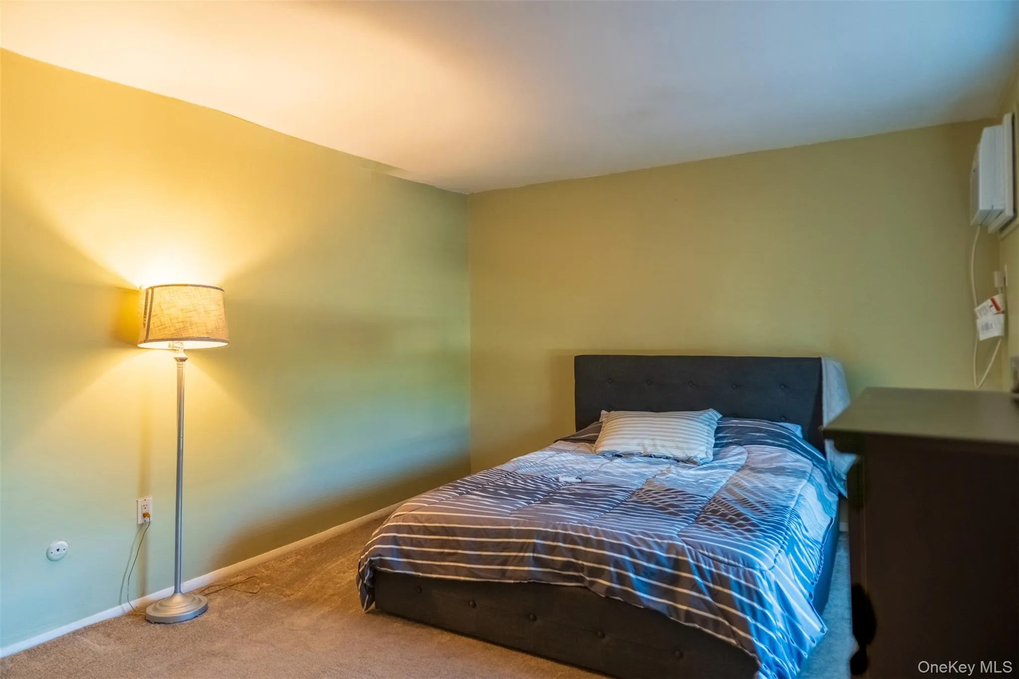Carpeted bedroom featuring baseboards and a wall unit AC Carpeted bedroom featuring baseboards and a wall unit AC