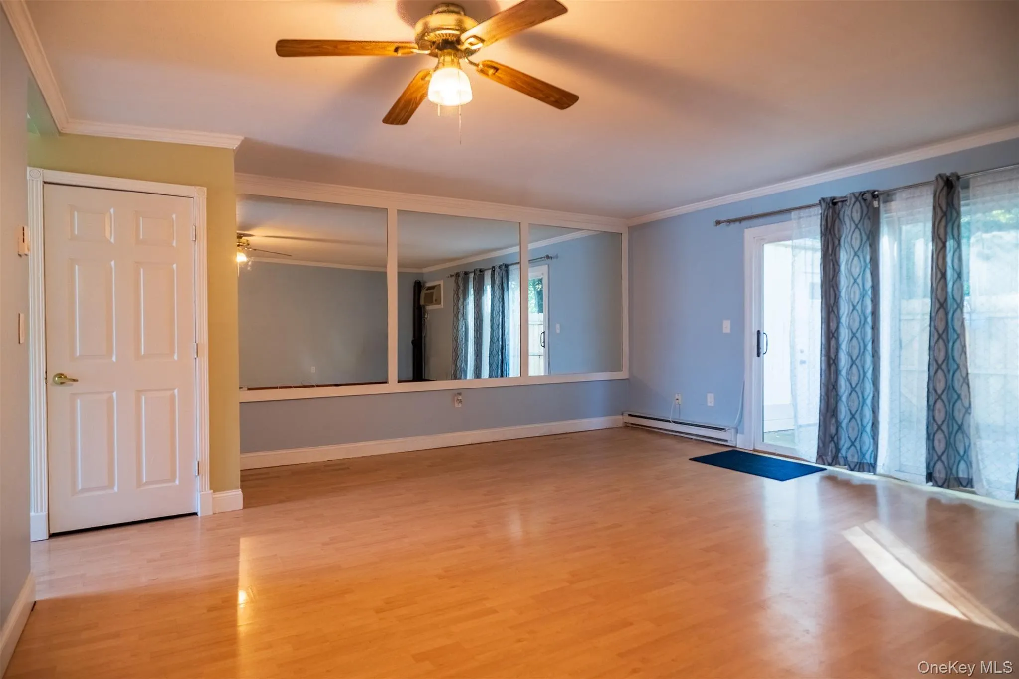 Spare room with crown molding, ceiling fan, light wood-style flooring, healthy amount of natural light, and a baseboard heating unit Spare room with crown molding, ceiling fan, light wood-style flooring, healthy amount of natural light, and a baseboard heating unit