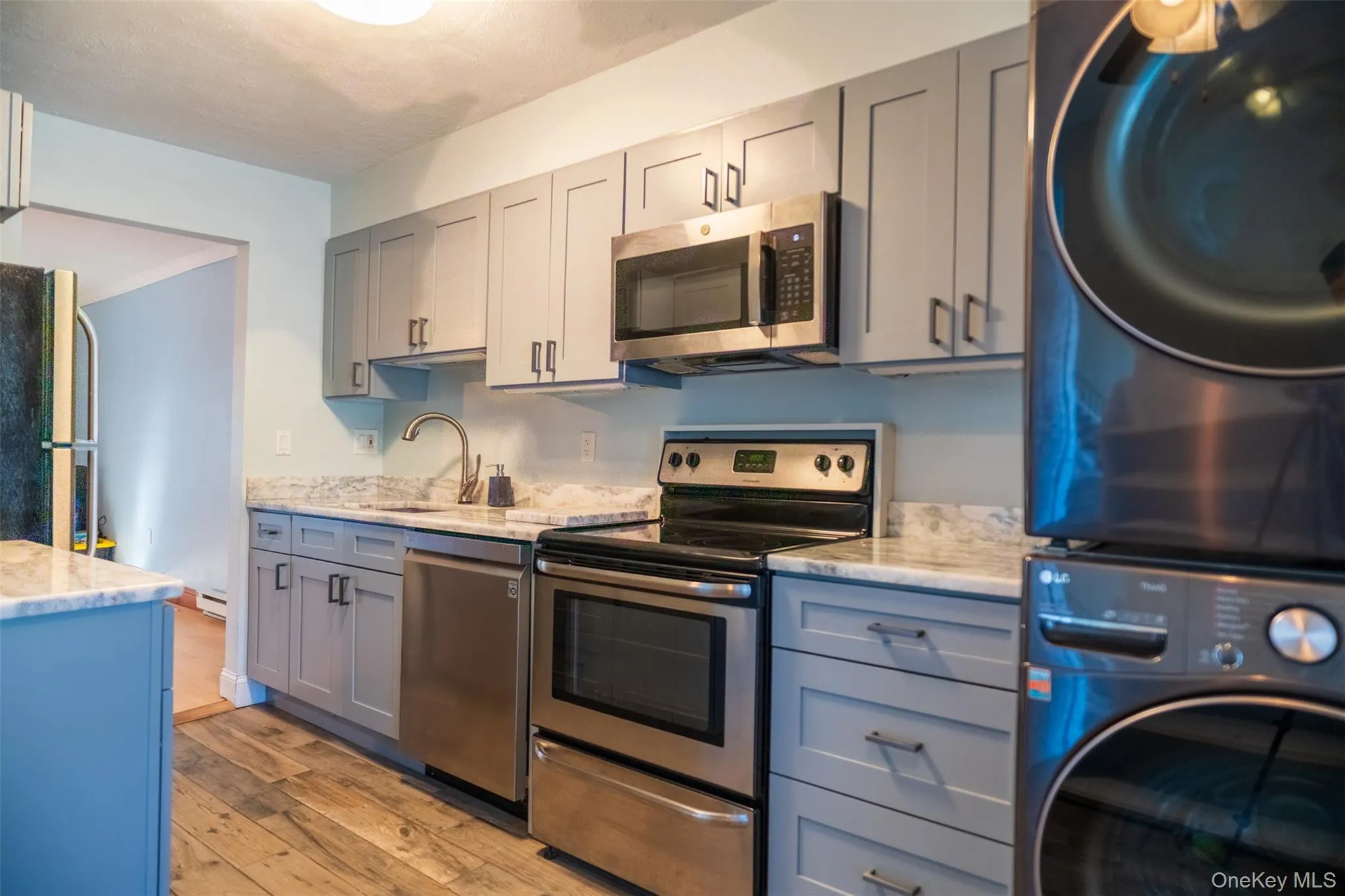 Kitchen featuring gray cabinetry, appliances with stainless steel finishes, and light wood-type flooring Kitchen featuring gray cabinetry, appliances with stainless steel finishes, and light wood-type flooring