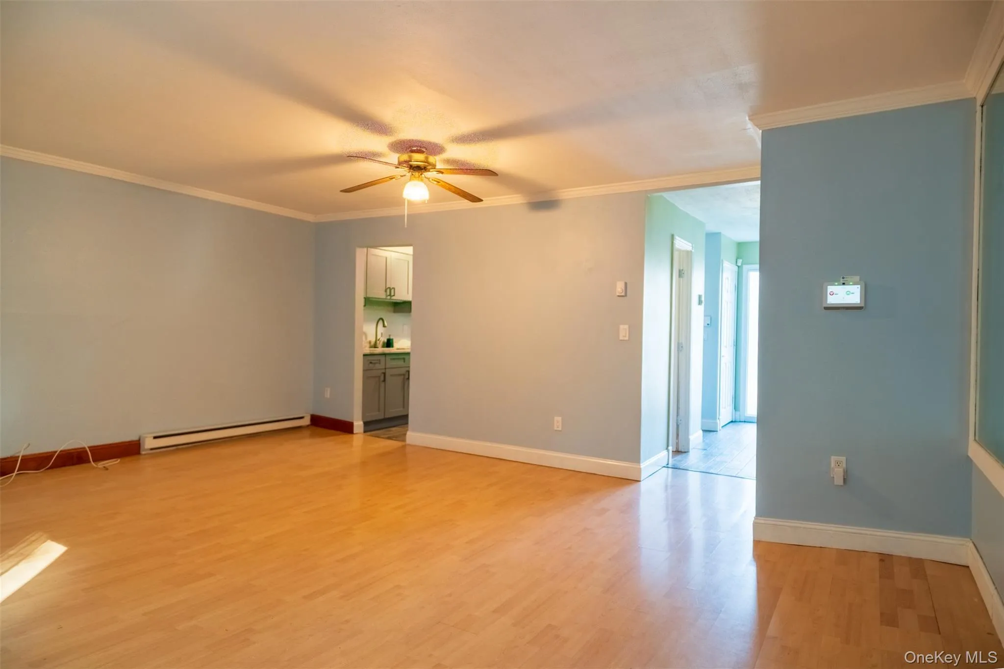 Spare room featuring crown molding, light wood-style floors, a baseboard radiator, and ceiling fan Spare room featuring crown molding, light wood-style floors, a baseboard radiator, and ceiling fan