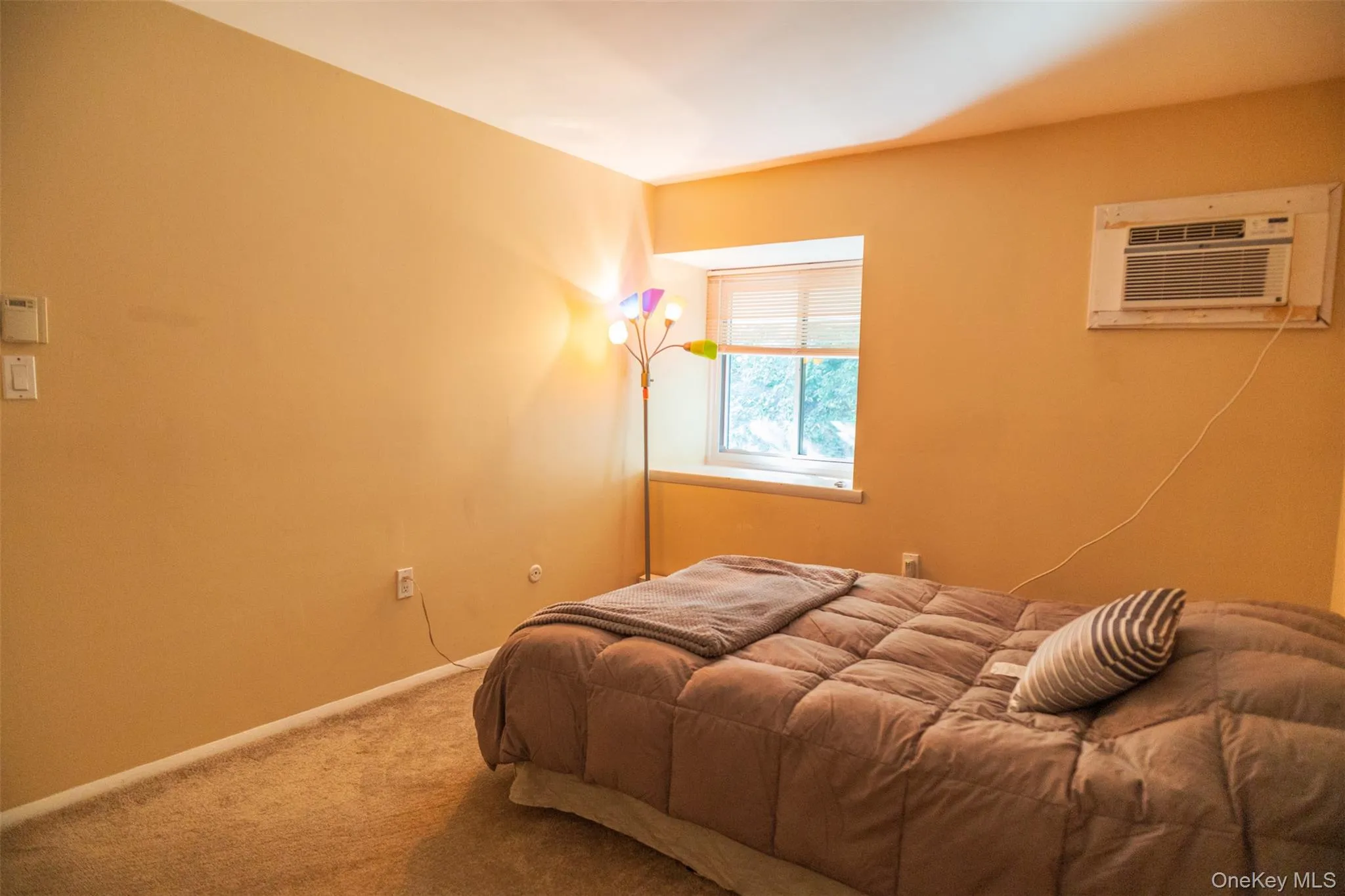 Bedroom with carpet and a wall mounted air conditioner Bedroom with carpet and a wall mounted air conditioner