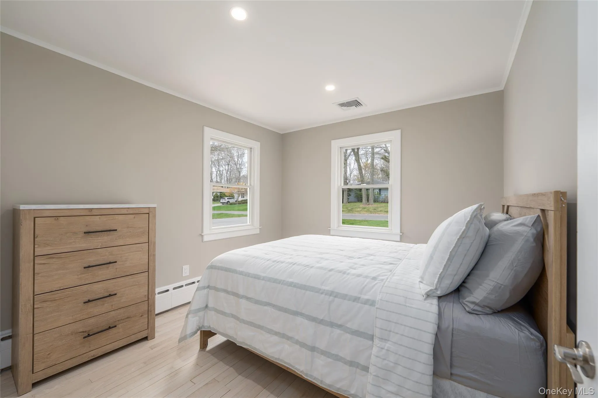 Bedroom featuring recessed lighting, visible vents, light wood-style flooring, ornamental molding, and a baseboard radiator Bedroom featuring recessed lighting, visible vents, light wood-style flooring, ornamental molding, and a baseboard radiator