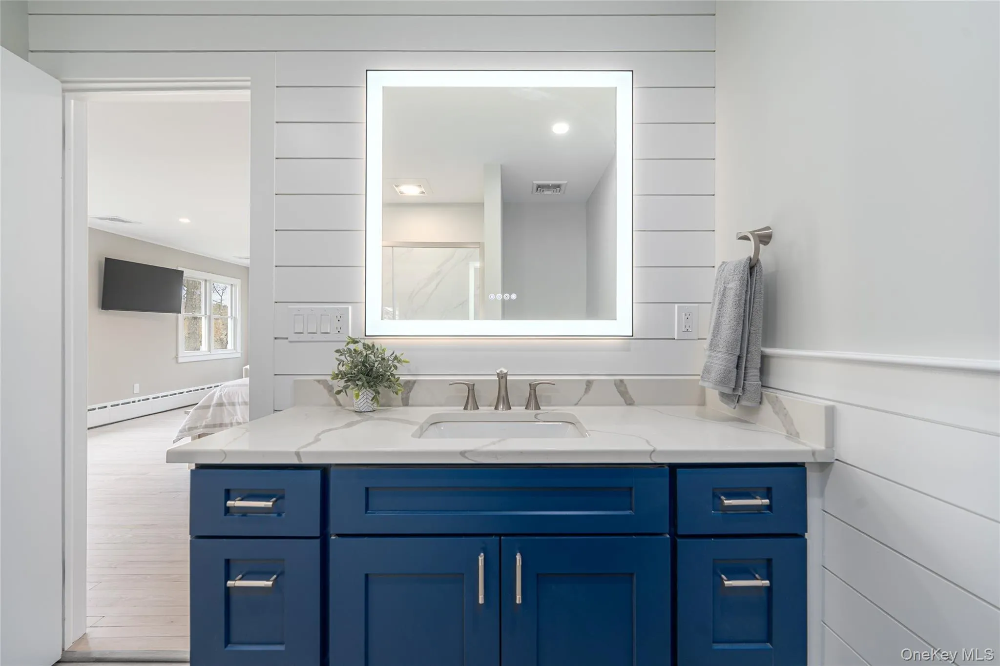 Bathroom with a baseboard radiator, visible vents, vanity, and wood finished floors Bathroom with a baseboard radiator, visible vents, vanity, and wood finished floors