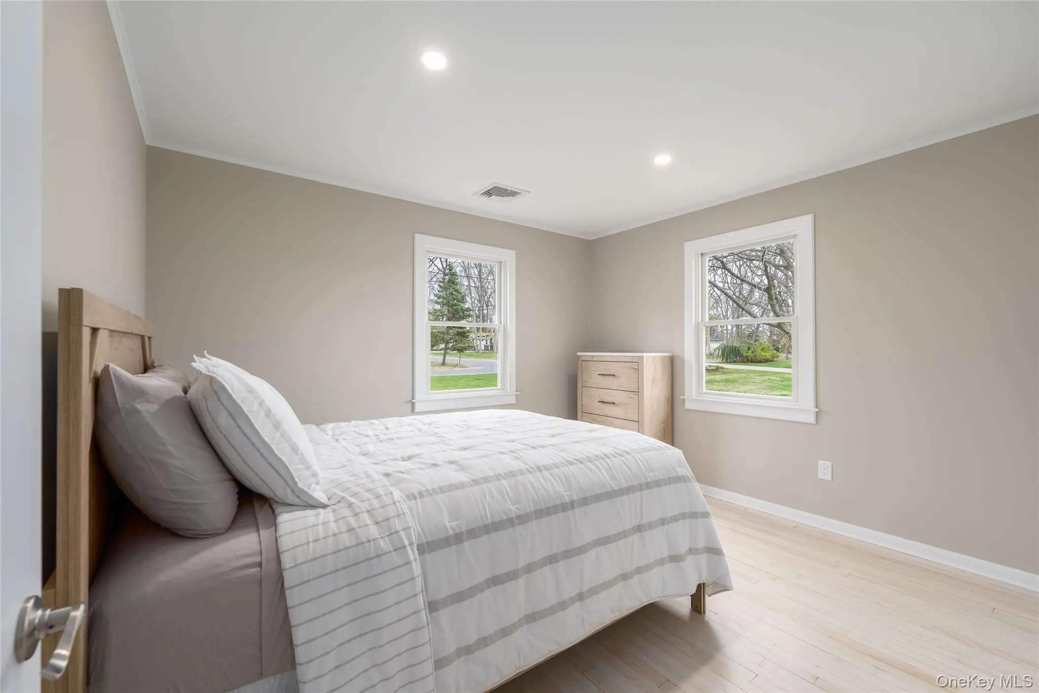 Bedroom with recessed lighting, light wood finished floors, baseboards, visible vents, and crown molding Bedroom with recessed lighting, light wood finished floors, baseboards, visible vents, and crown molding