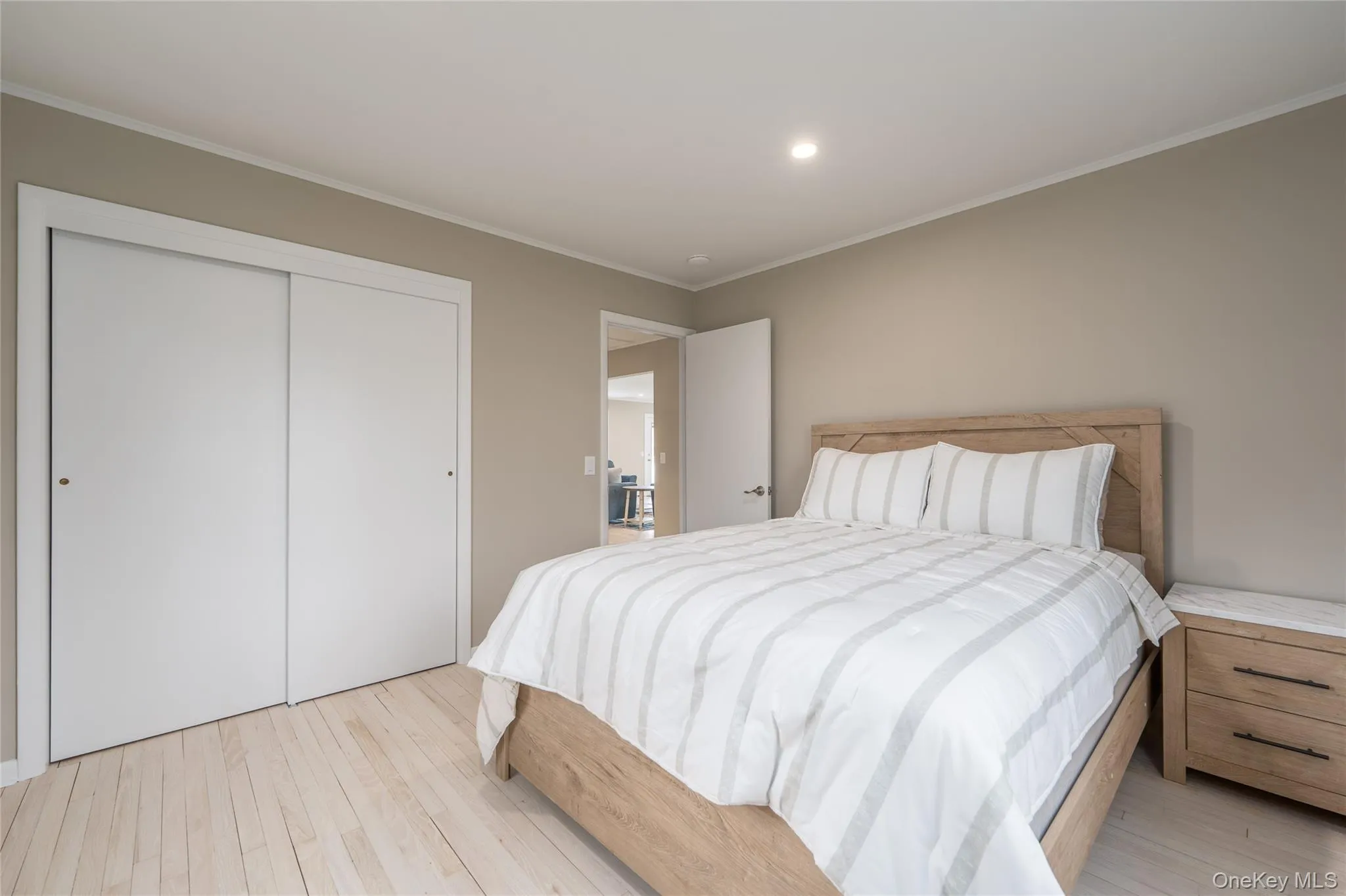 Bedroom with crown molding, a closet, and light wood-type flooring Bedroom with crown molding, a closet, and light wood-type flooring