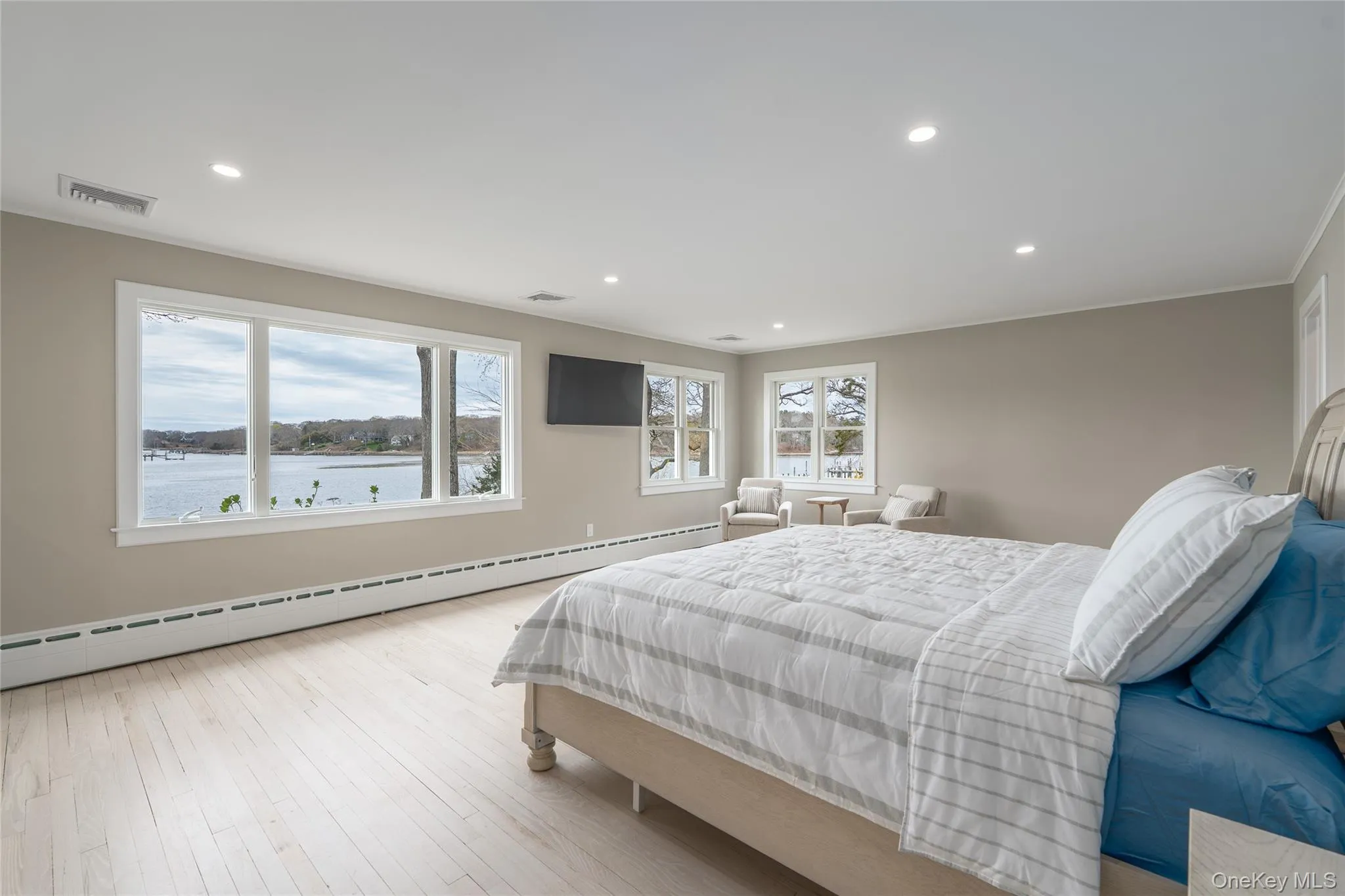 Bedroom featuring visible vents, recessed lighting, wood finished floors, and a baseboard heating unit Bedroom featuring visible vents, recessed lighting, wood finished floors, and a baseboard heating unit