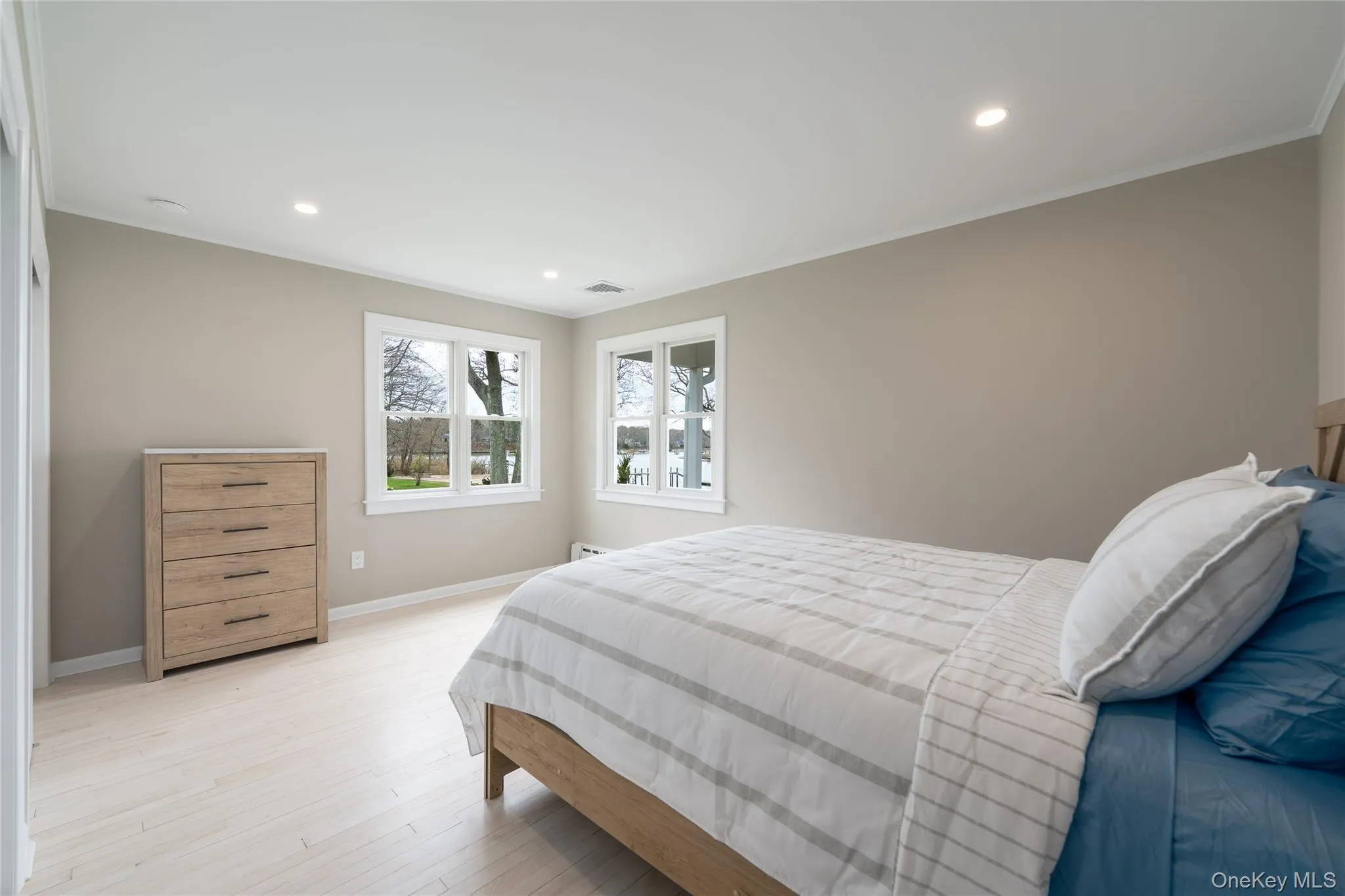 Bedroom with recessed lighting, crown molding, visible vents, light wood-style flooring, and baseboards Bedroom with recessed lighting, crown molding, visible vents, light wood-style flooring, and baseboards