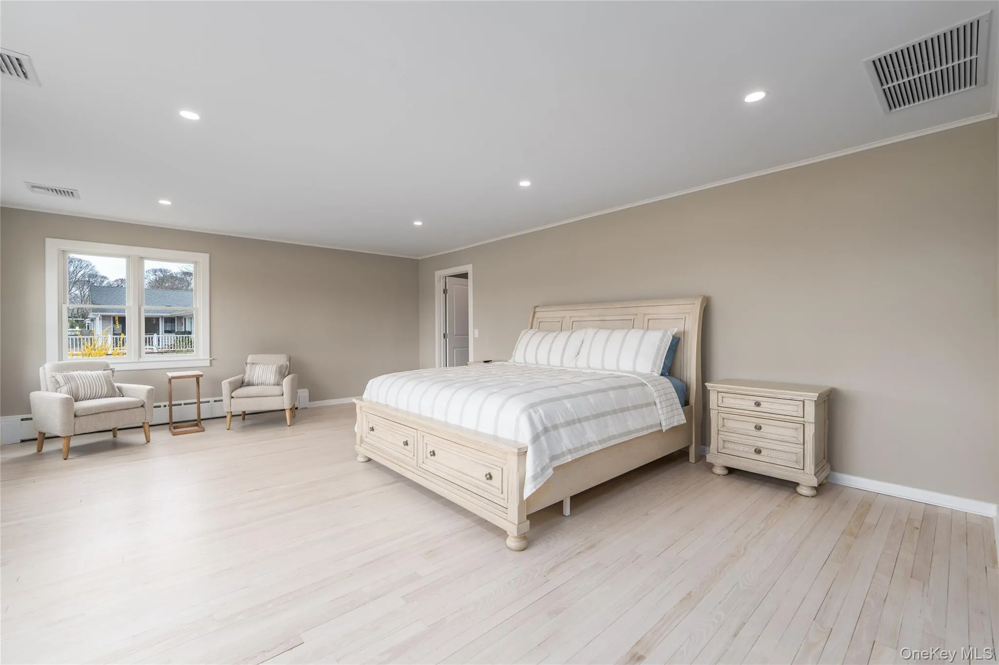 Bedroom with a baseboard heating unit, light wood-style floors, baseboards, visible vents, and crown molding Bedroom with a baseboard heating unit, light wood-style floors, baseboards, visible vents, and crown molding