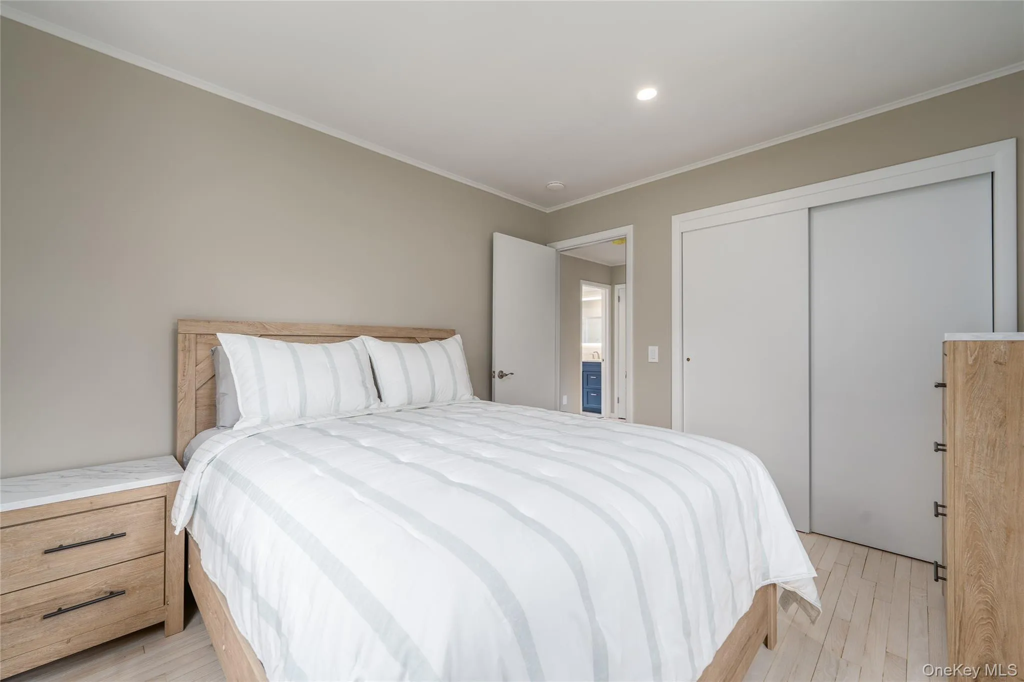 Bedroom with light wood-type flooring, crown molding, recessed lighting, and a closet Bedroom with light wood-type flooring, crown molding, recessed lighting, and a closet