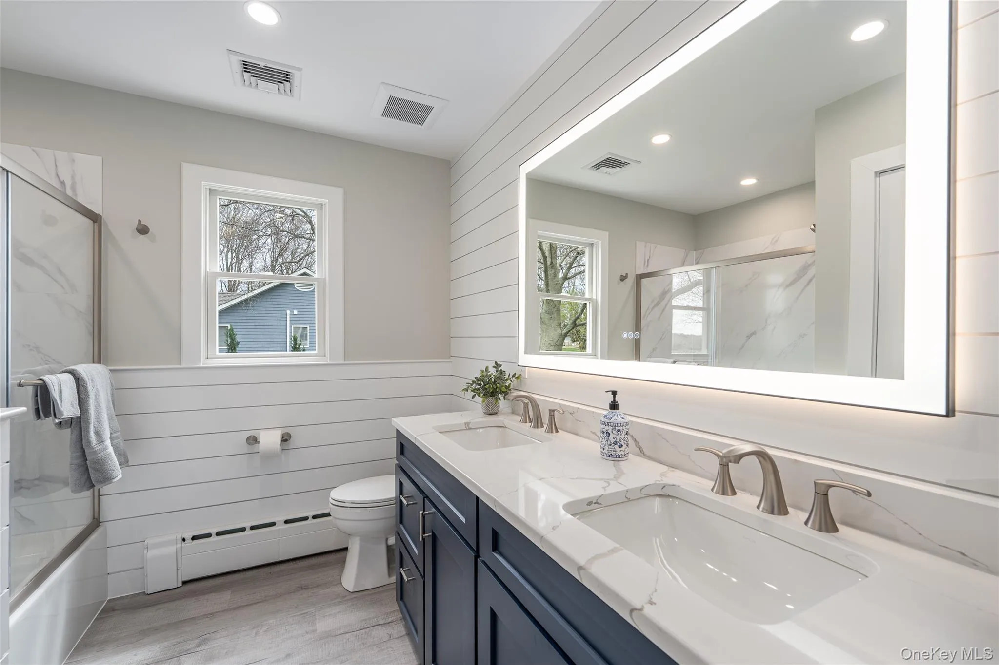 Bathroom featuring a baseboard heating unit, a sink, and visible vents Bathroom featuring a baseboard heating unit, a sink, and visible vents