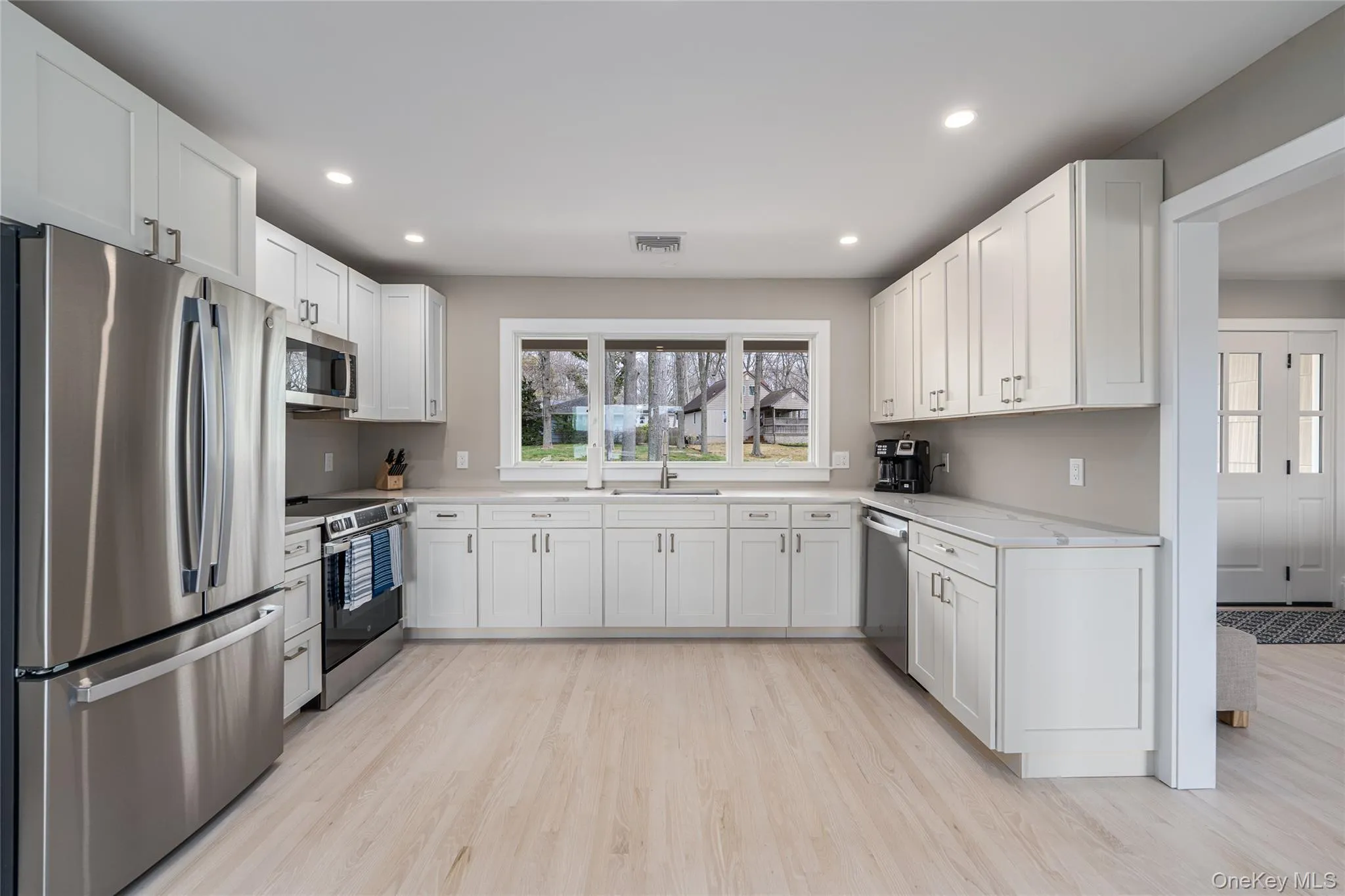 Kitchen featuring white cabinets, appliances with stainless steel finishes, visible vents, light wood-type flooring, and recessed lighting Kitchen featuring white cabinets, appliances with stainless steel finishes, visible vents, light wood-type flooring, and recessed lighting