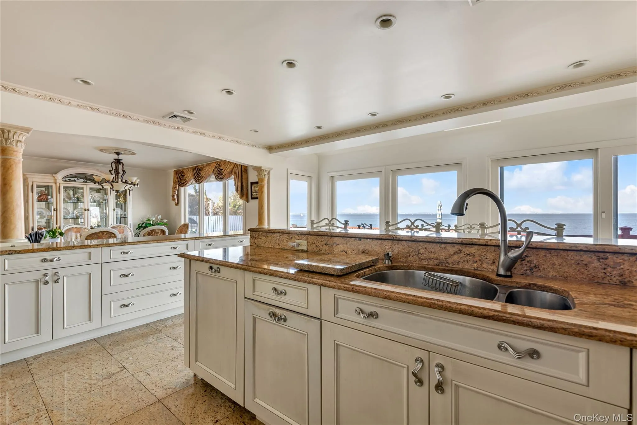 Kitchen featuring cream cabinets, dark stone countertops, a chandelier, and a water view Kitchen featuring cream cabinets, dark stone countertops, a chandelier, and a water view
