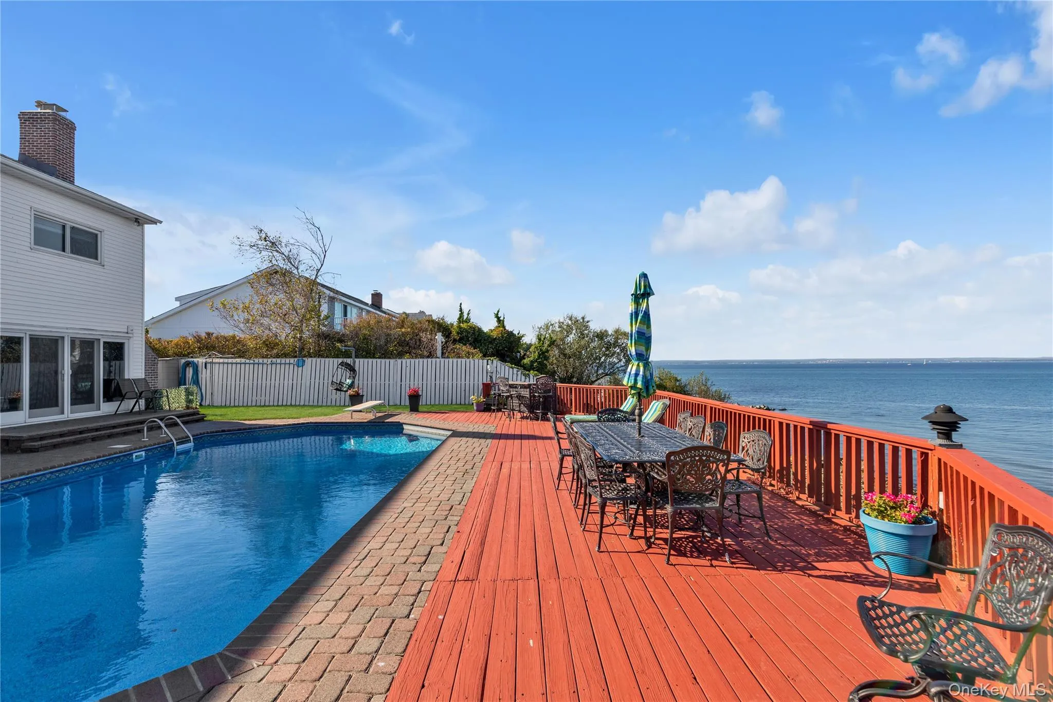 View of pool featuring outdoor dining space, a patio area, a deck with water view, and a fenced backyard View of pool featuring outdoor dining space, a patio area, a deck with water view, and a fenced backyard