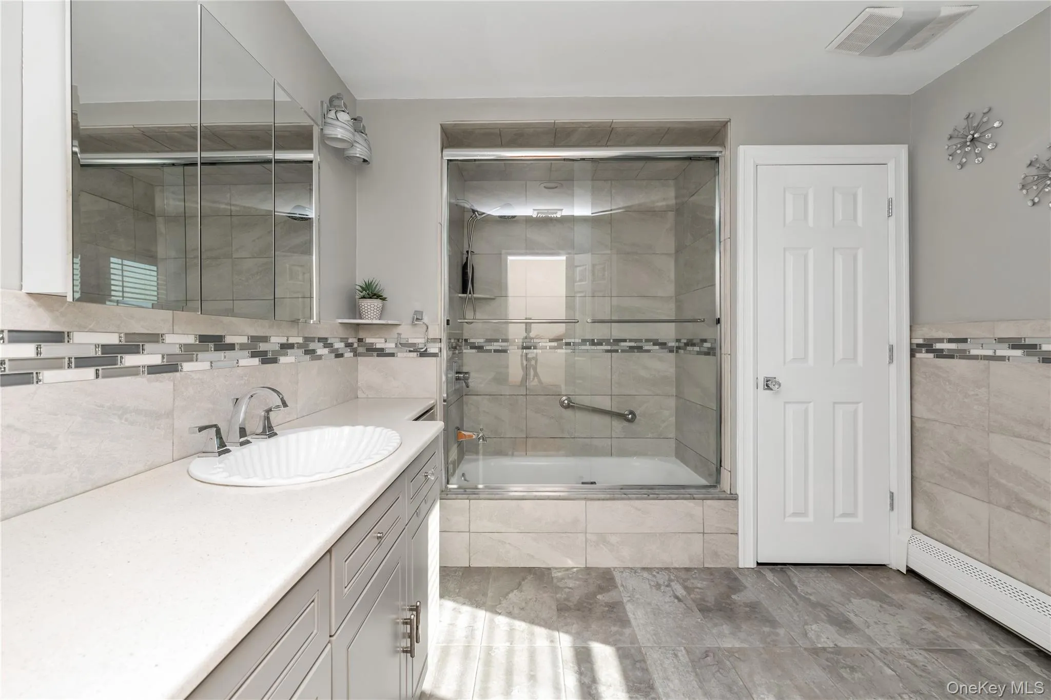 Bathroom with tiled shower / bath, tile walls, vanity, and a baseboard heating unit Bathroom with tiled shower / bath, tile walls, vanity, and a baseboard heating unit