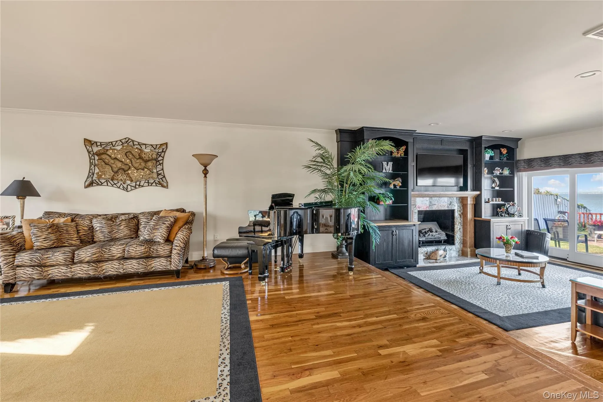 Living room featuring ornamental molding, wood finished floors, and a premium fireplace Living room featuring ornamental molding, wood finished floors, and a premium fireplace