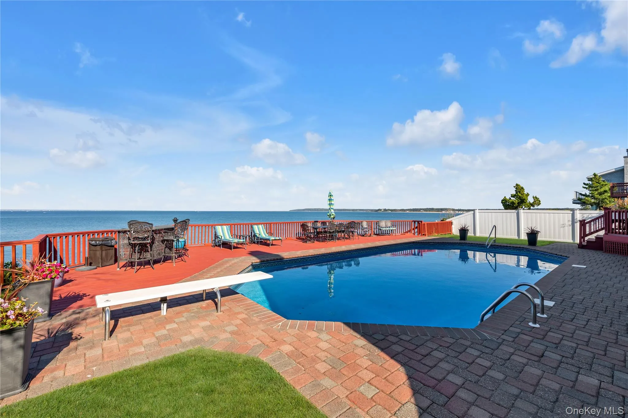 View of pool featuring a water view, a diving board, a patio, and outdoor dining area View of pool featuring a water view, a diving board, a patio, and outdoor dining area
