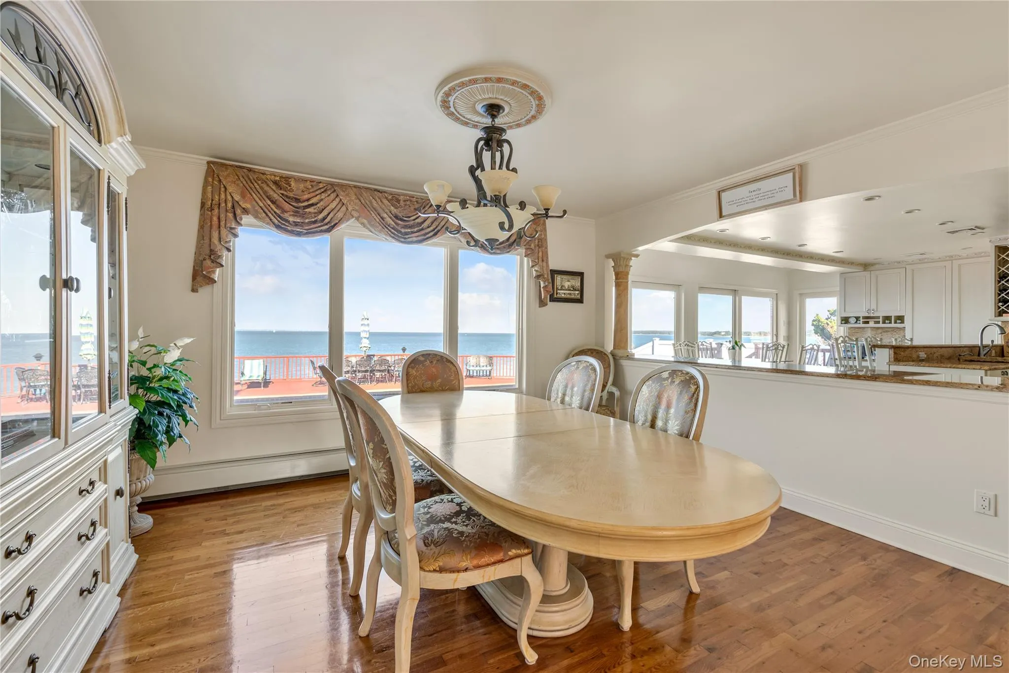 Dining room featuring light wood-style flooring, a water view, ornamental molding, a baseboard heating unit, and a chandelier Dining room featuring light wood-style flooring, a water view, ornamental molding, a baseboard heating unit, and a chandelier