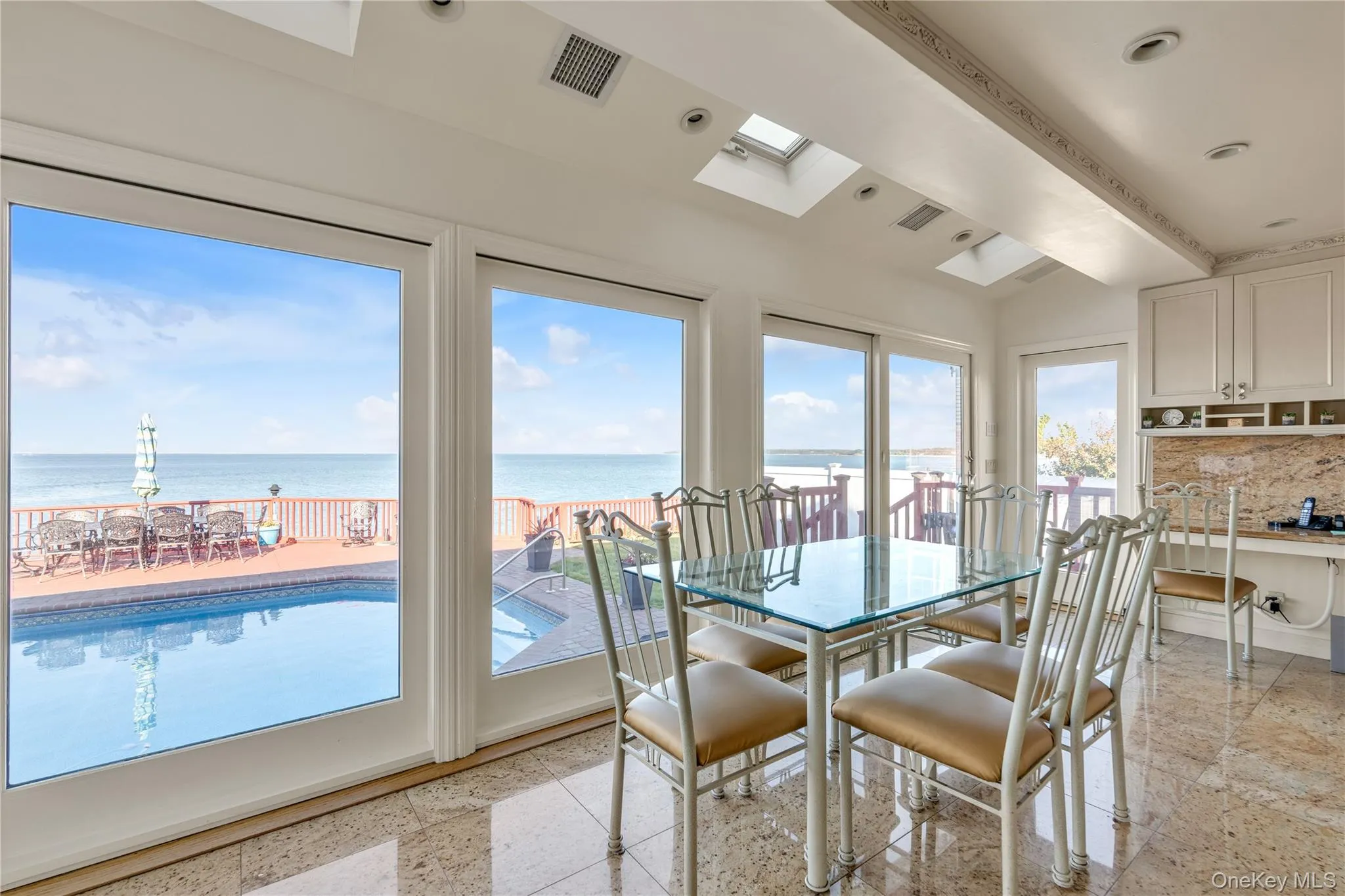 Dining area with a water view, beam ceiling, and a skylight Dining area with a water view, beam ceiling, and a skylight