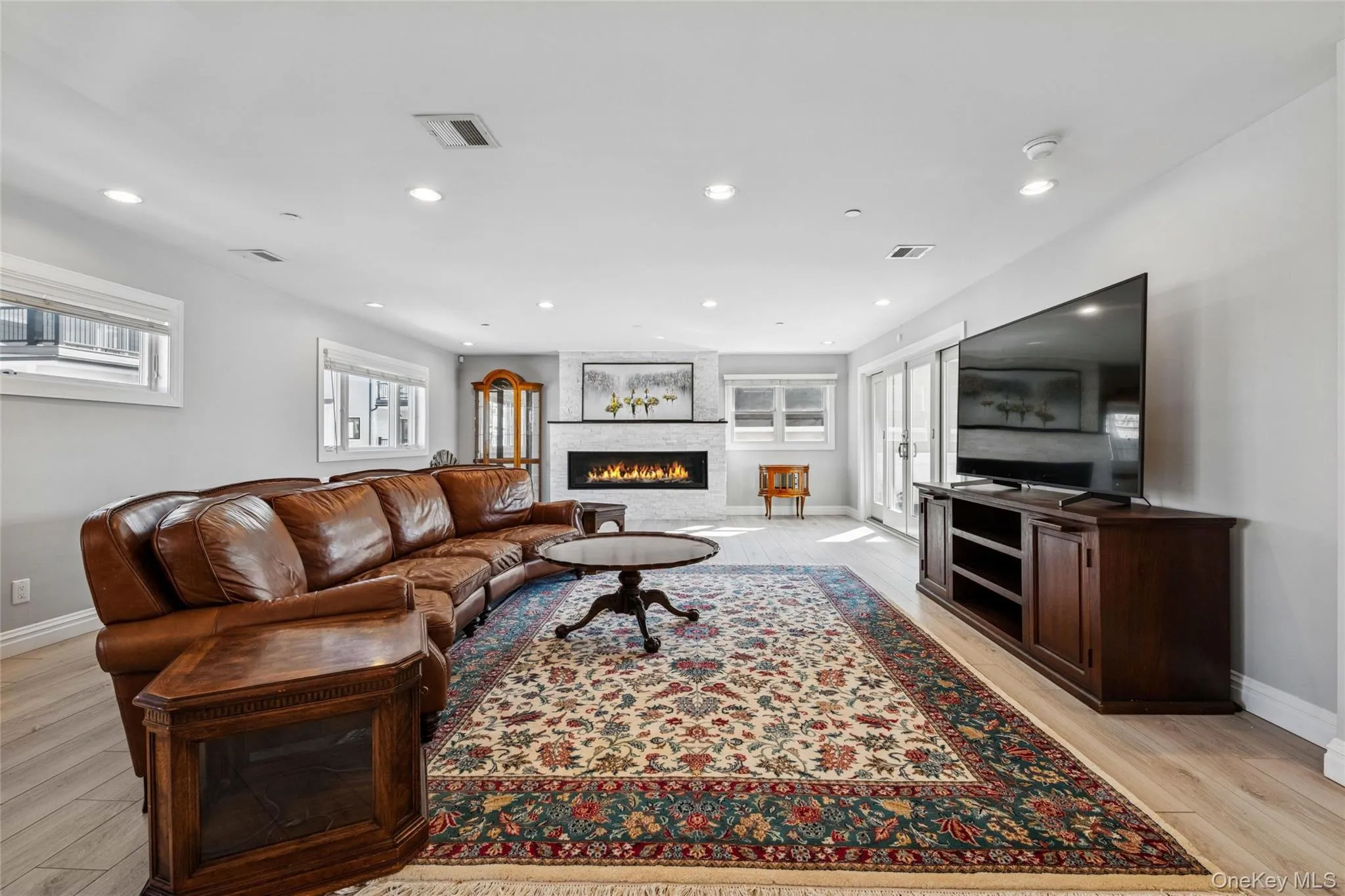 Living area featuring light wood finished floors, recessed lighting, and a large fireplace Living area featuring light wood finished floors, recessed lighting, and a large fireplace