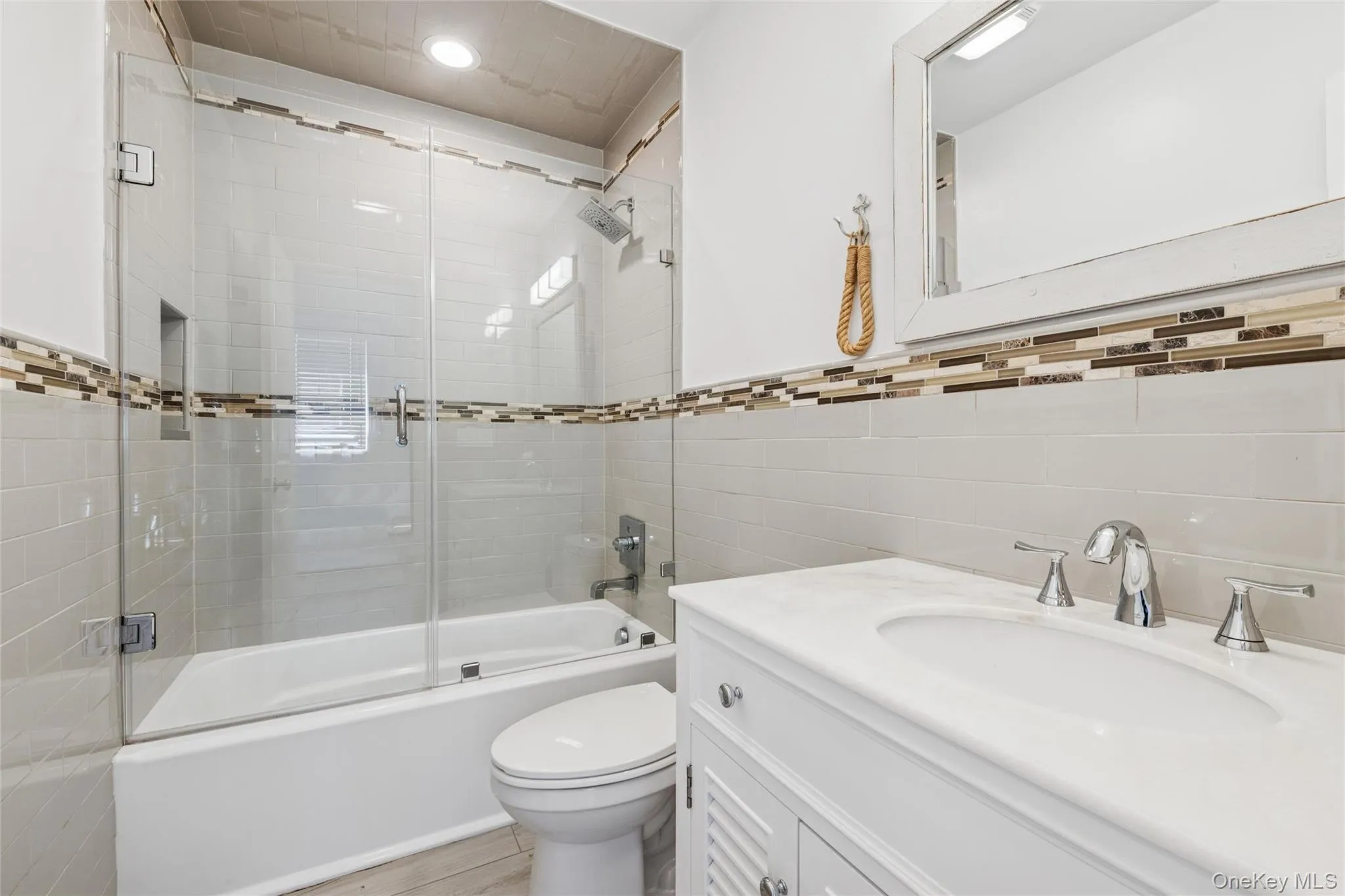 Full bathroom with combined bath / shower with glass door, tile walls, and vanity Full bathroom with combined bath / shower with glass door, tile walls, and vanity