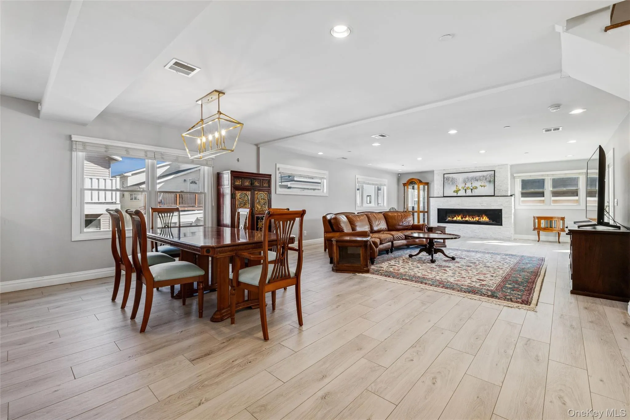 Dining area featuring light wood-style flooring, recessed lighting, and a lit fireplace Dining area featuring light wood-style flooring, recessed lighting, and a lit fireplace