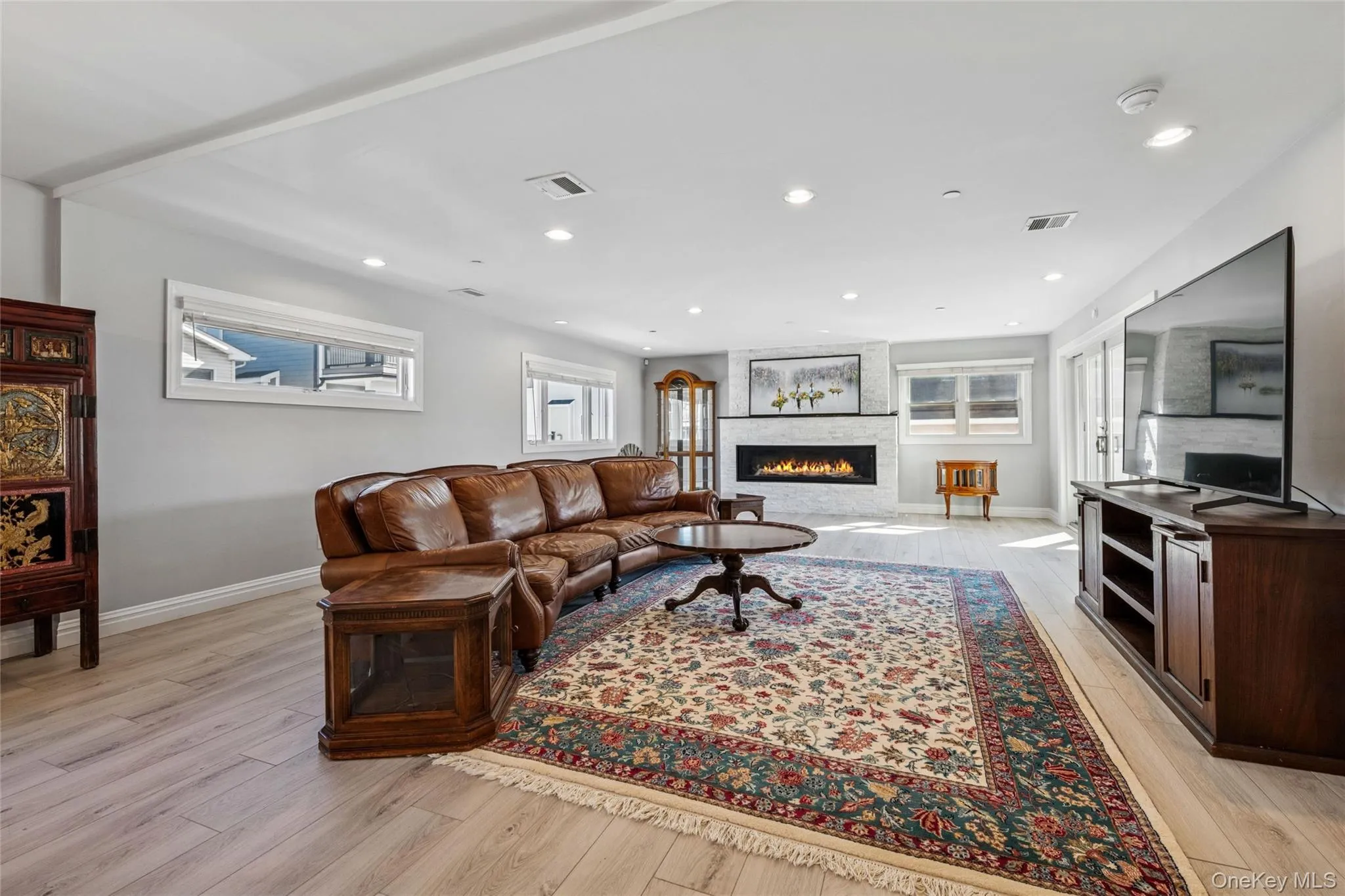 Living area featuring light wood-type flooring, a large fireplace, and recessed lighting Living area featuring light wood-type flooring, a large fireplace, and recessed lighting