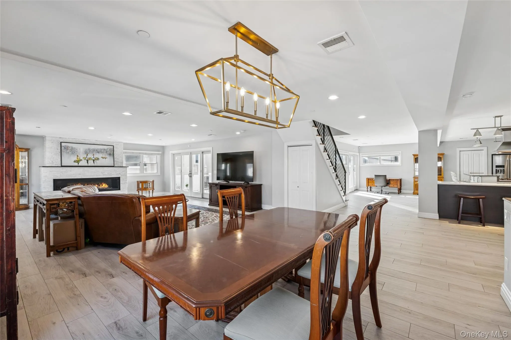 Dining space with a large fireplace, stairs, light wood-style floors, plenty of natural light, and recessed lighting Dining space with a large fireplace, stairs, light wood-style floors, plenty of natural light, and recessed lighting