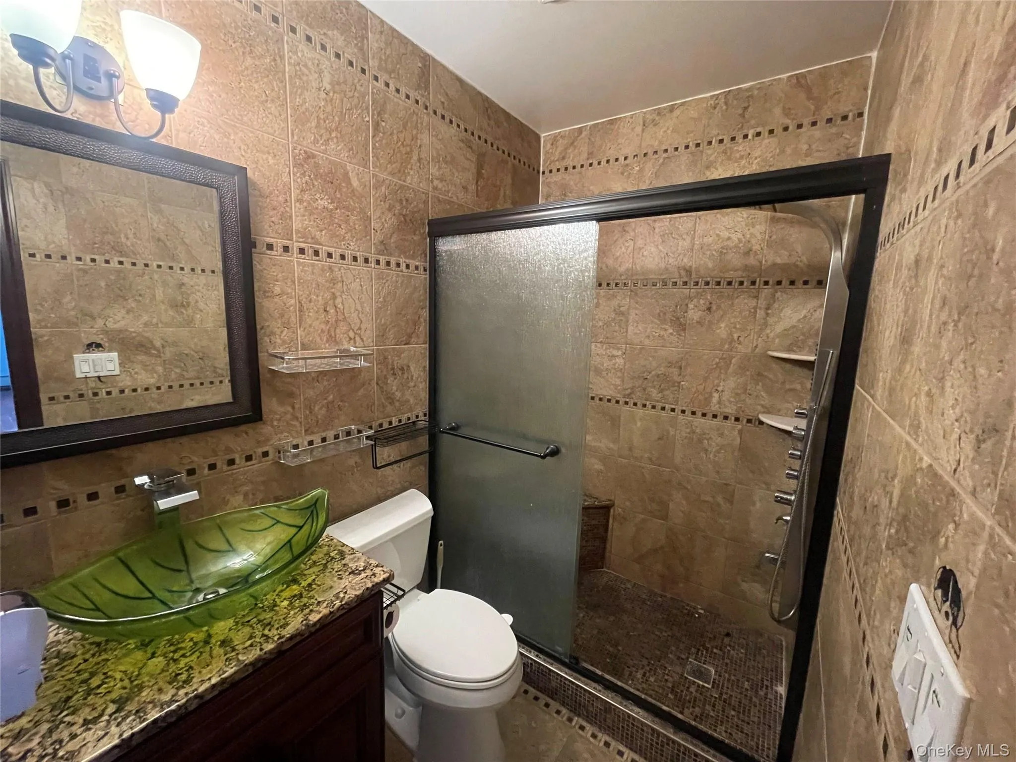 Full bath with tile walls, a stall shower, vanity, and tasteful backsplash Full bath with tile walls, a stall shower, vanity, and tasteful backsplash