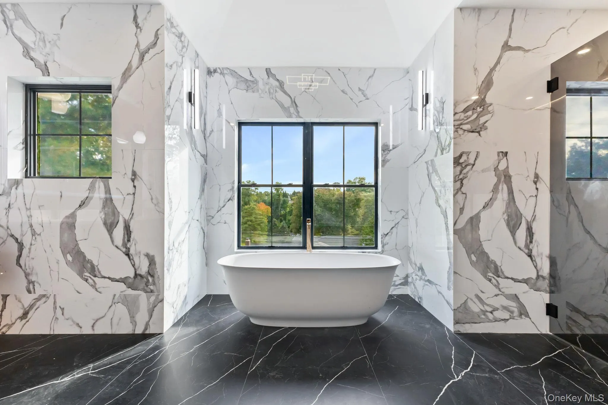 Full bath with stone wall, plenty of natural light, and a freestanding tub Full bath with stone wall, plenty of natural light, and a freestanding tub