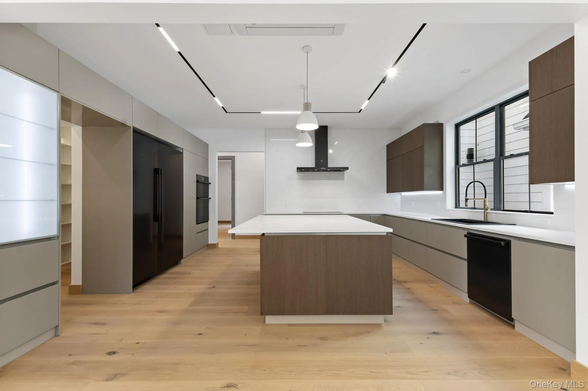 Kitchen featuring Scavolini cabinets, a center island, pendant lighting, light wood-type flooring, and black Dacor appliances Kitchen featuring Scavolini cabinets, a center island, pendant lighting, light wood-type flooring, and black Dacor appliances