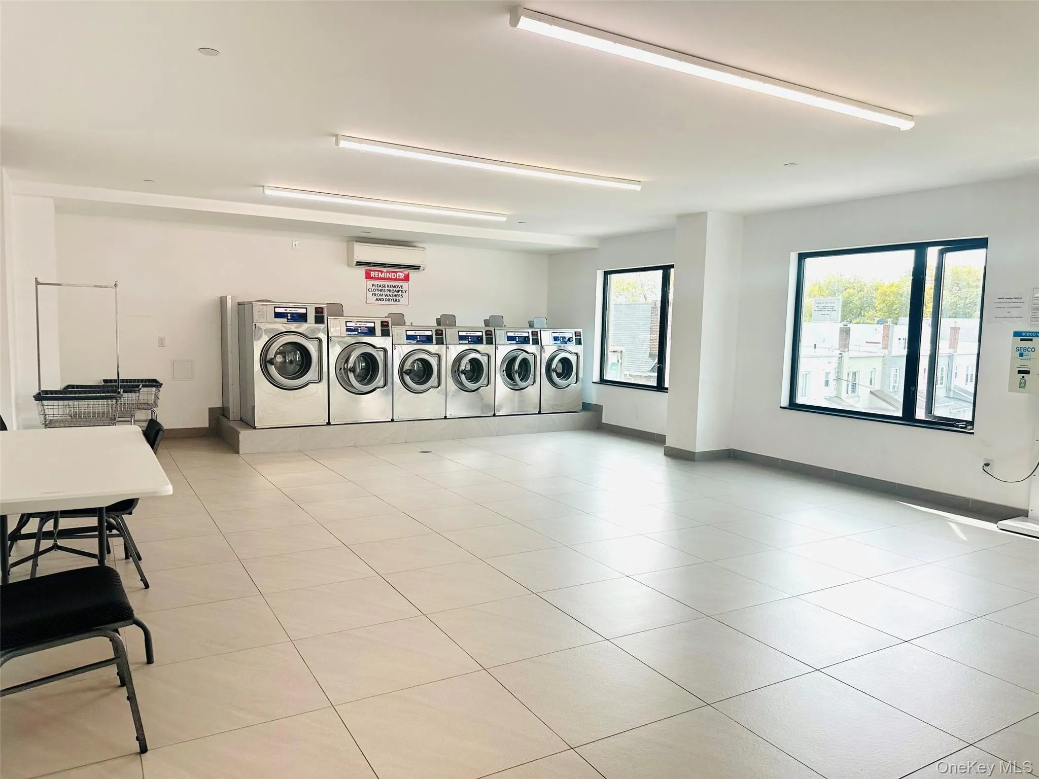 Shared laundry featuring an AC wall unit and washing machine and clothes dryer Shared laundry featuring an AC wall unit and washing machine and clothes dryer