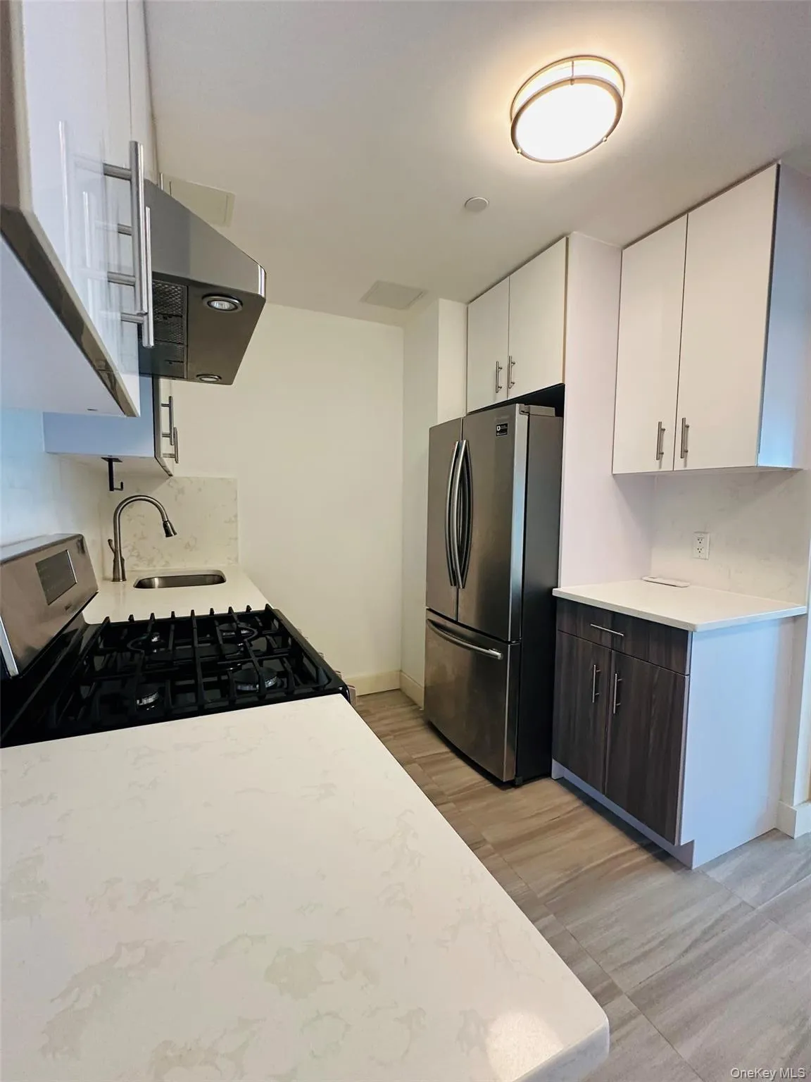 Kitchen featuring white cabinetry, stainless steel appliances, range hood, and light stone countertops Kitchen featuring white cabinetry, stainless steel appliances, range hood, and light stone countertops