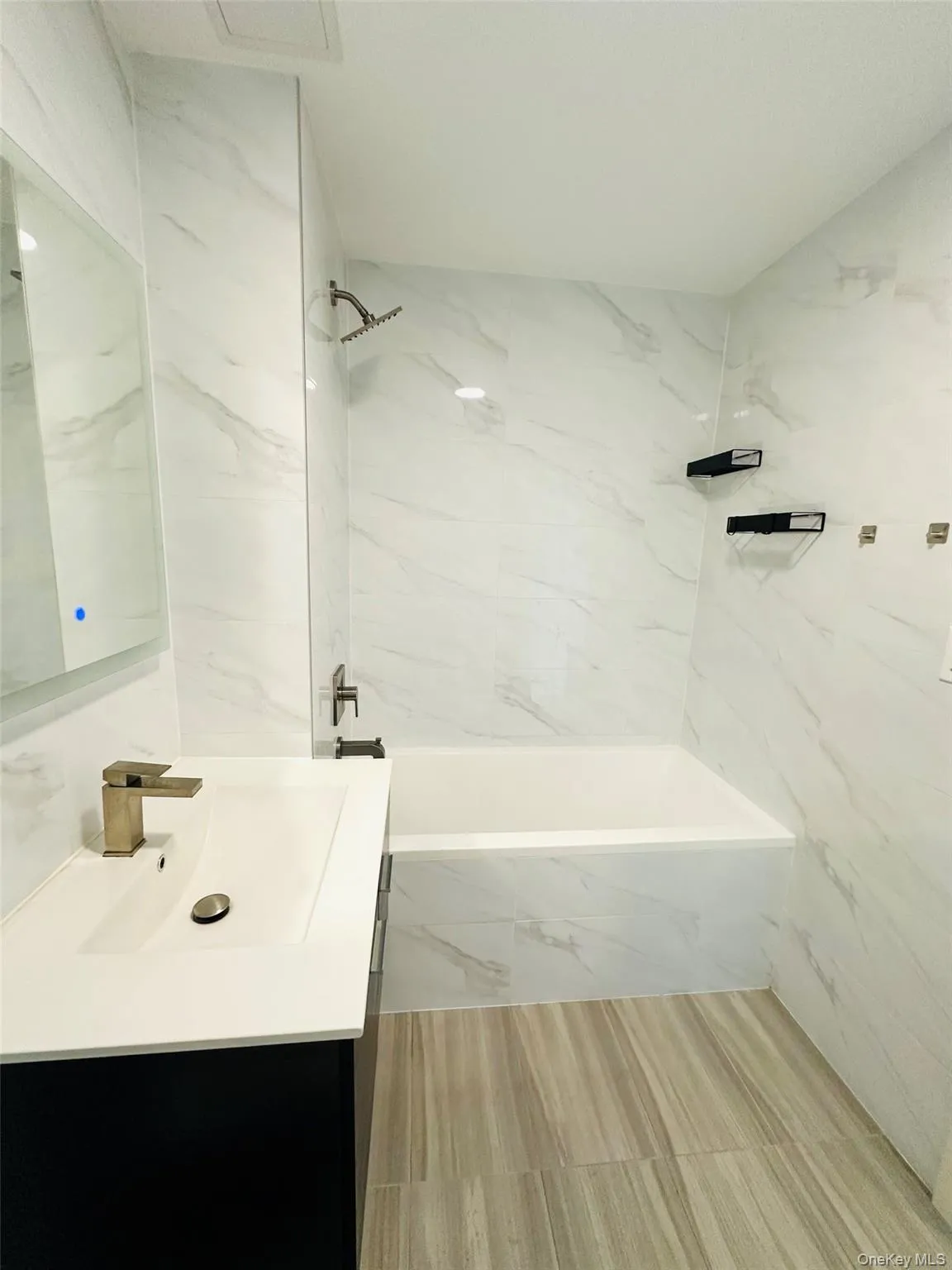 Full bath with a combined bath / shower with marble appearance, vanity, and tile walls Full bath with a combined bath / shower with marble appearance, vanity, and tile walls