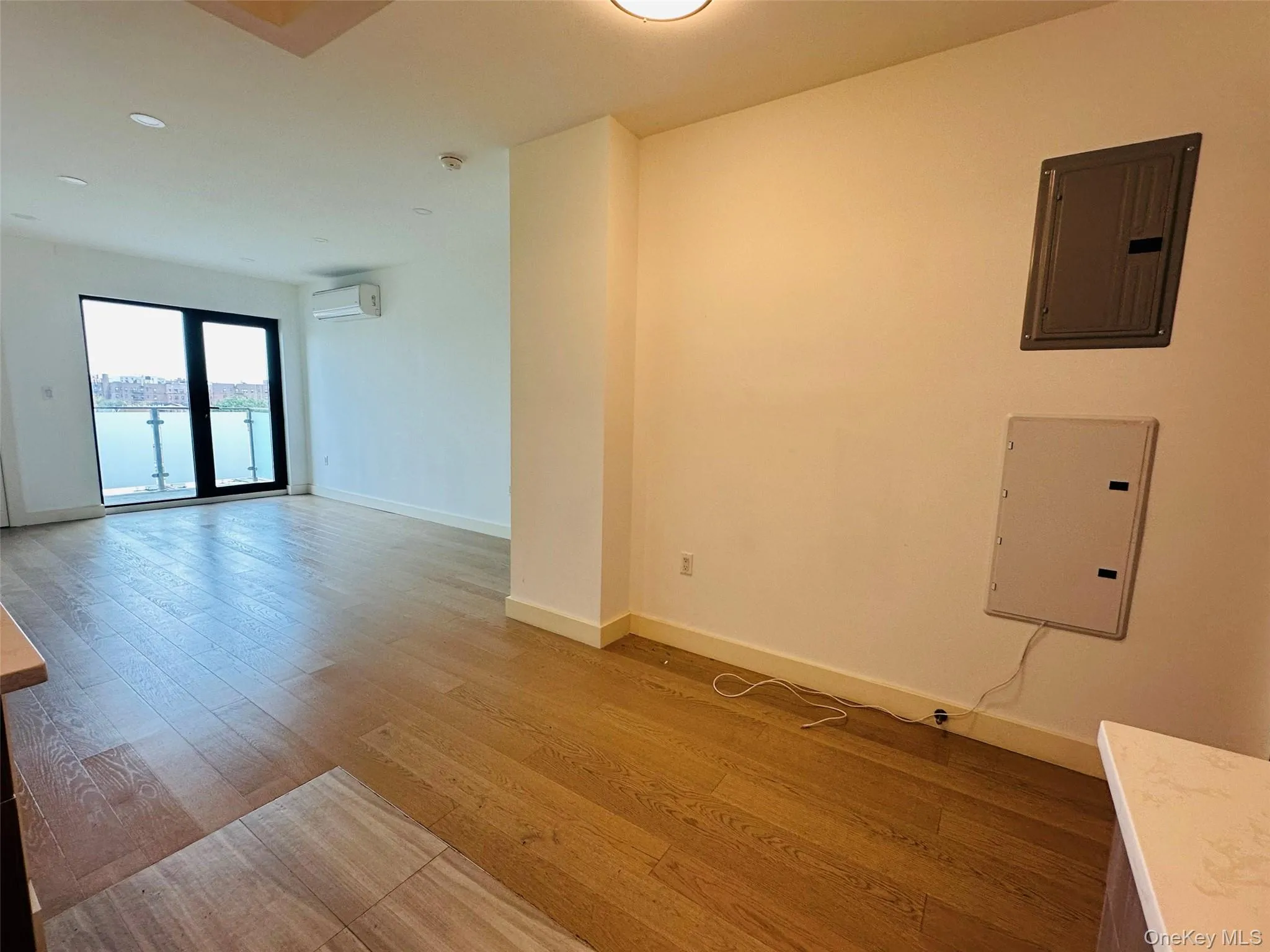 Unfurnished room featuring electric panel, wood finished floors, a wall unit AC, and a water view Unfurnished room featuring electric panel, wood finished floors, a wall unit AC, and a water view