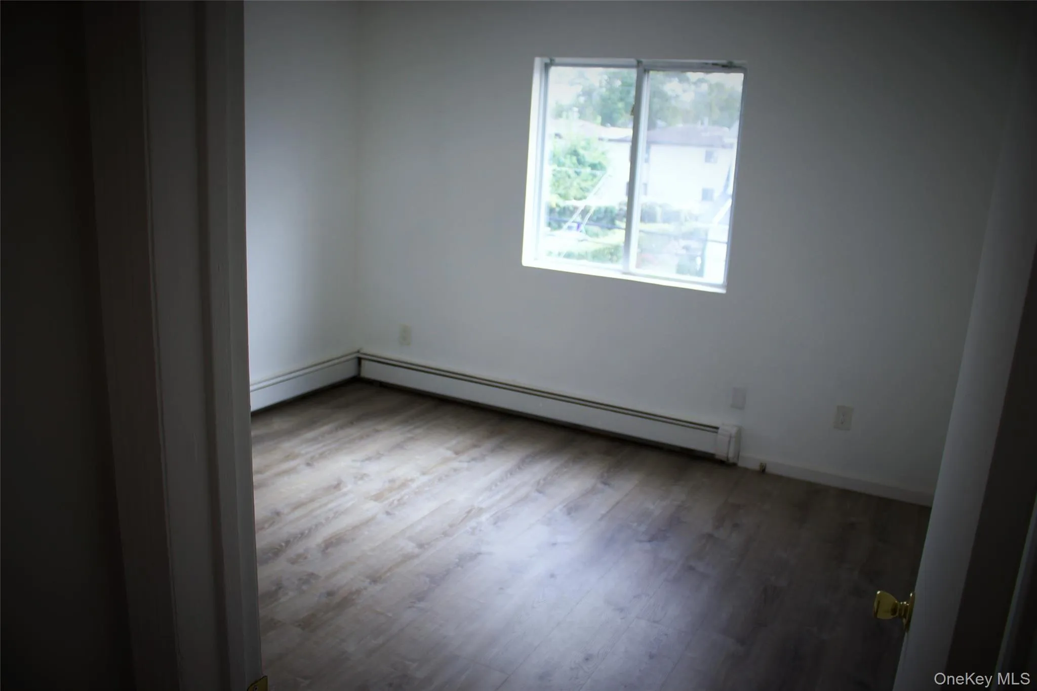Unfurnished room with light wood-style flooring, a baseboard heating unit, and a baseboard radiator Unfurnished room with light wood-style flooring, a baseboard heating unit, and a baseboard radiator