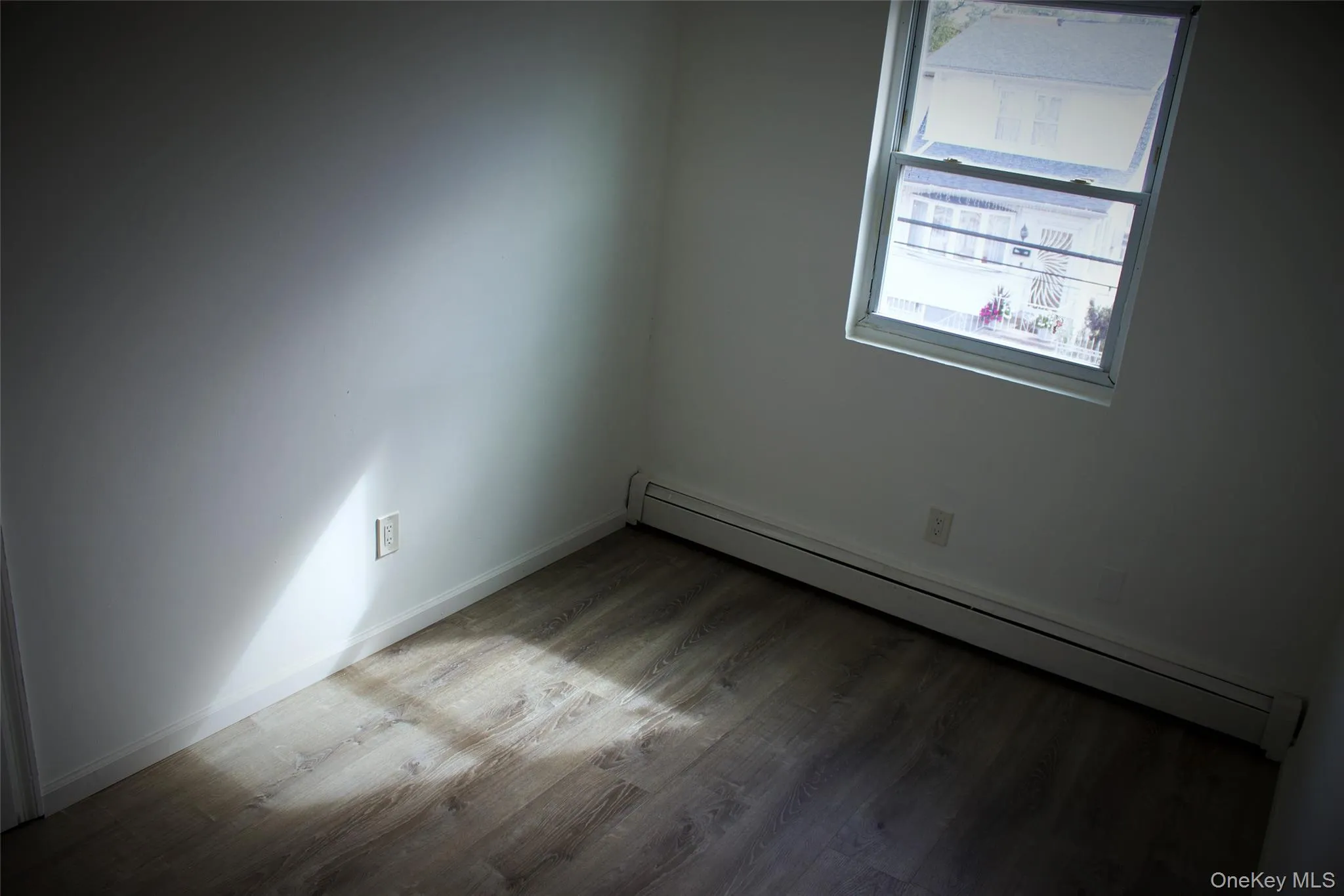 Spare room with a baseboard heating unit and wood finished floors Spare room with a baseboard heating unit and wood finished floors