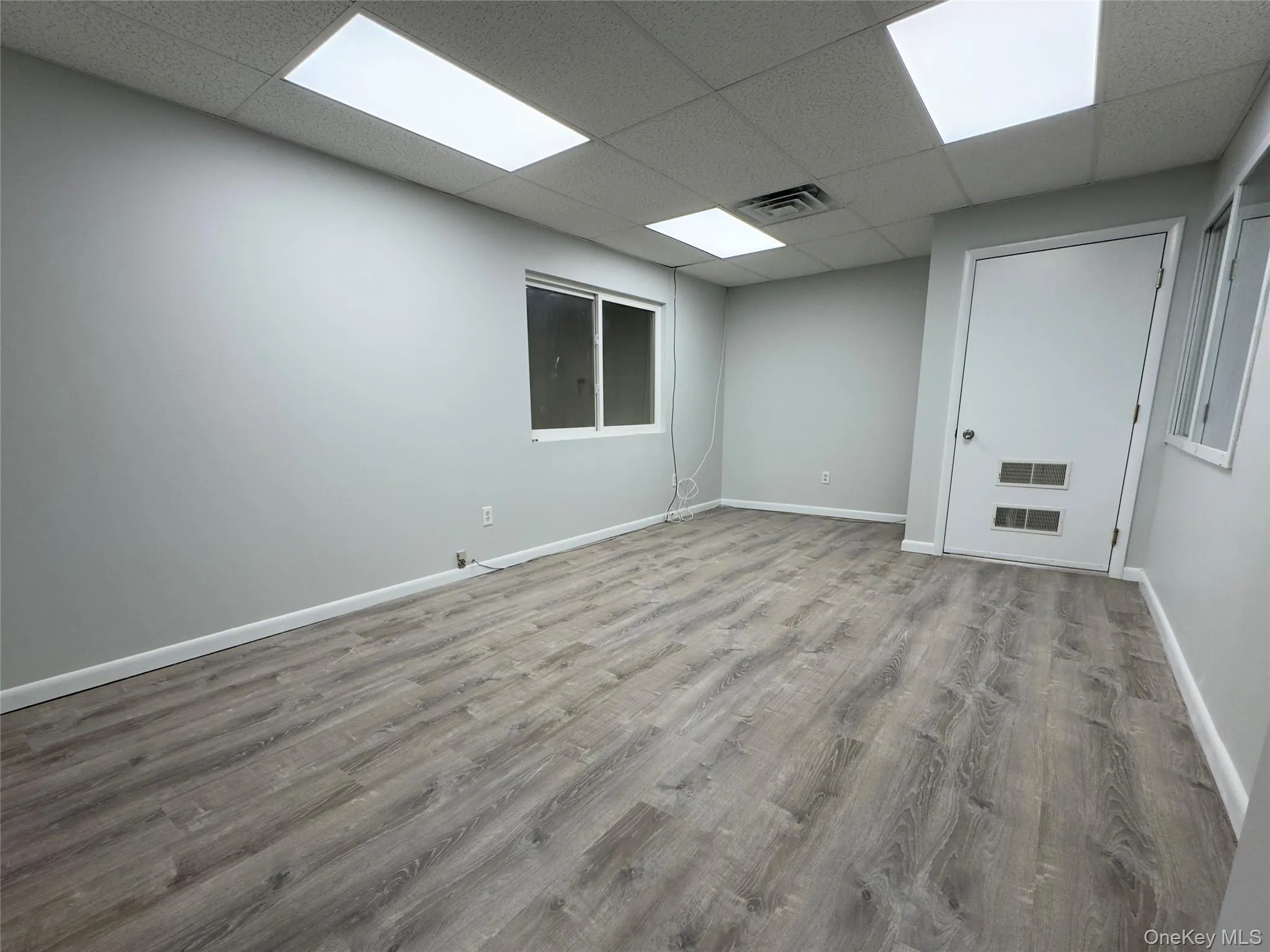 Spare room featuring wood finished floors and a paneled ceiling Spare room featuring wood finished floors and a paneled ceiling