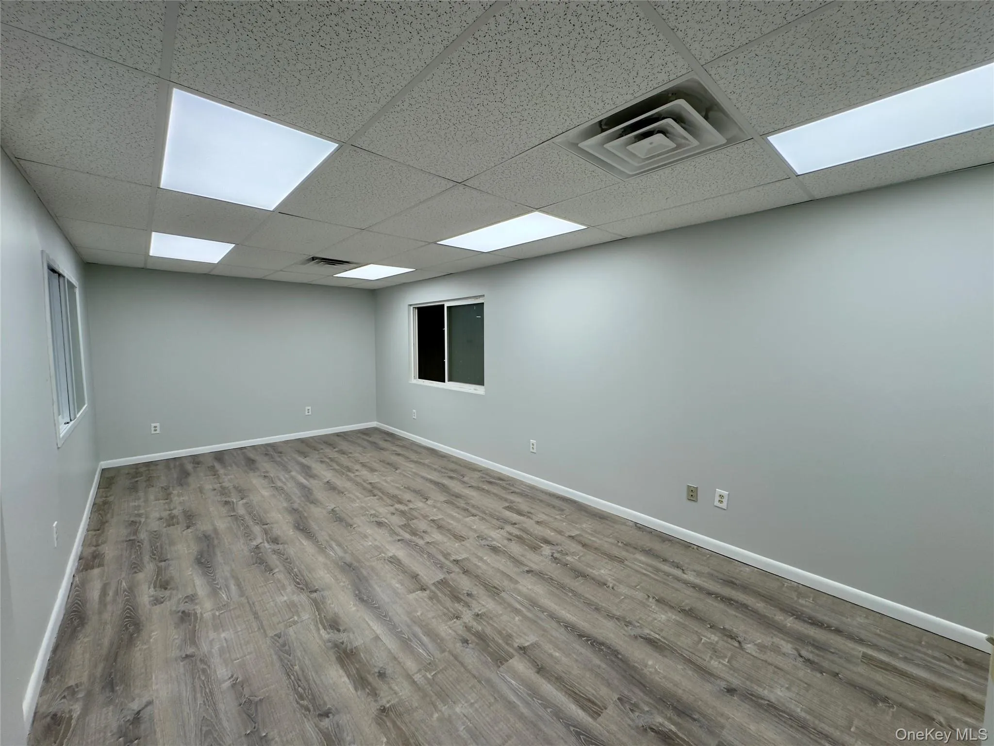 Spare room featuring light wood-style floors and a paneled ceiling Spare room featuring light wood-style floors and a paneled ceiling