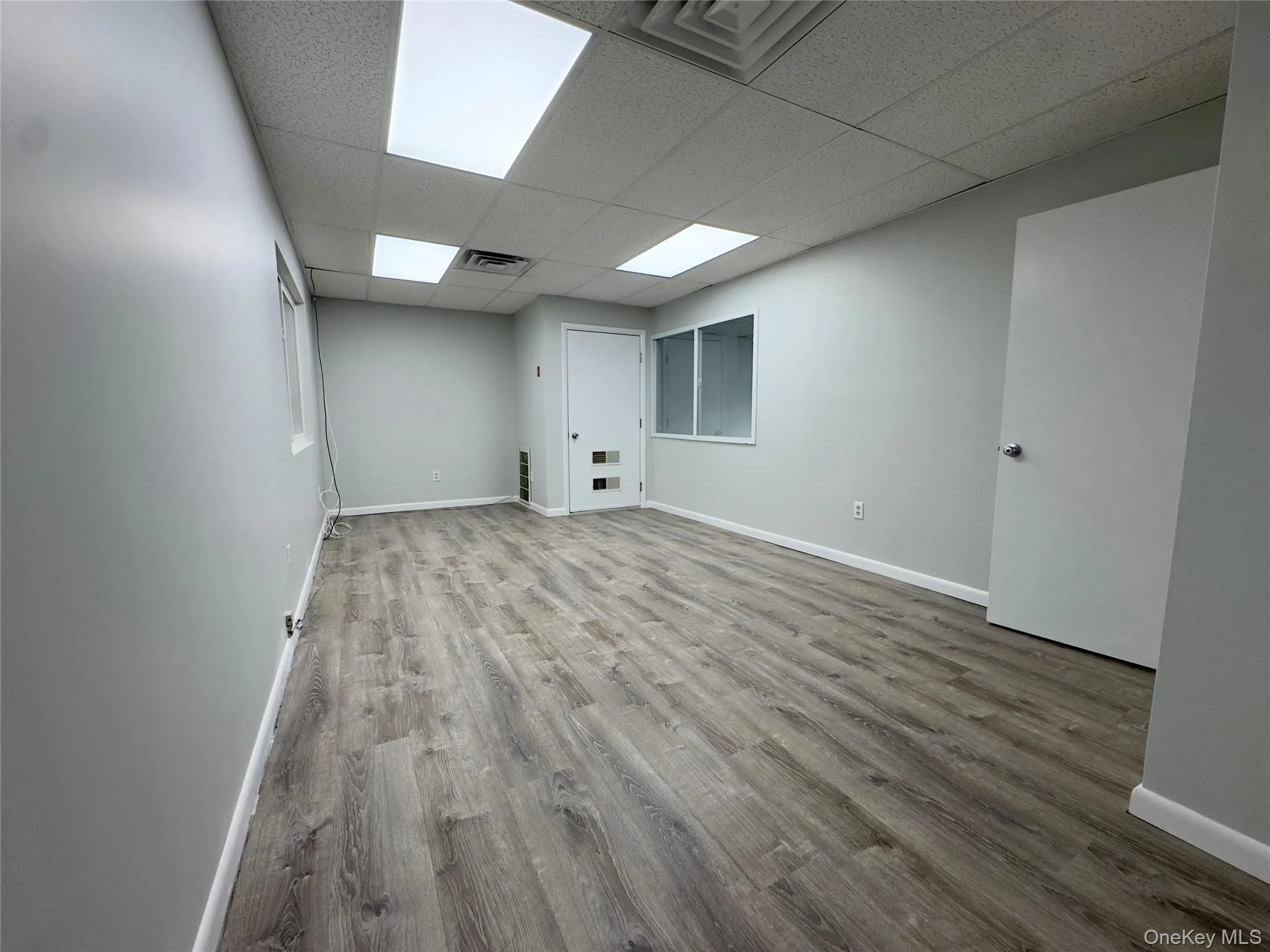 Unfurnished room with light wood-style floors and a drop ceiling Unfurnished room with light wood-style floors and a drop ceiling