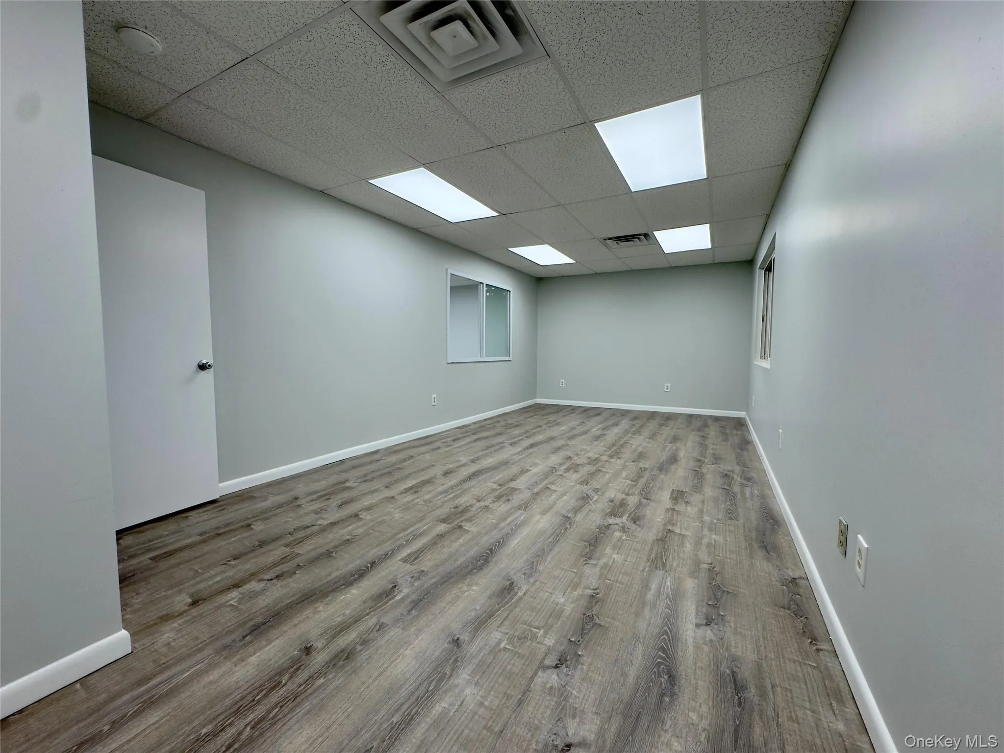 Unfurnished room with light wood-style floors and a drop ceiling Unfurnished room with light wood-style floors and a drop ceiling