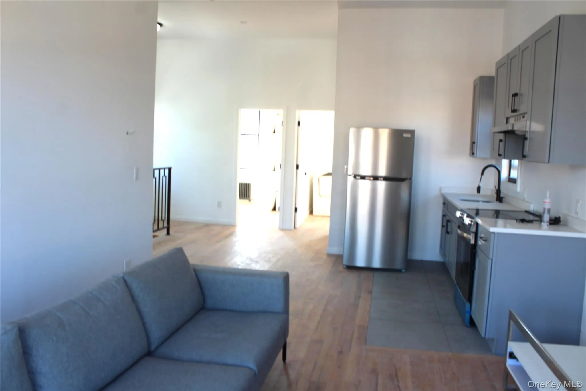 Kitchen with light countertops, stainless steel appliances, gray cabinetry, dark wood-style floors, and under cabinet range hood Kitchen with light countertops, stainless steel appliances, gray cabinetry, dark wood-style floors, and under cabinet range hood