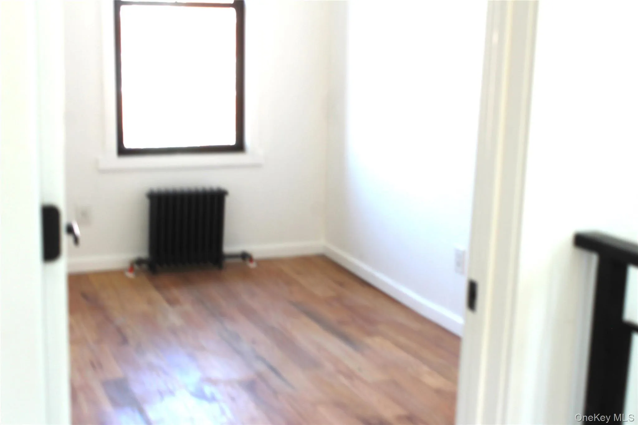 Unfurnished room with radiator heating unit and wood finished floors Unfurnished room with radiator heating unit and wood finished floors